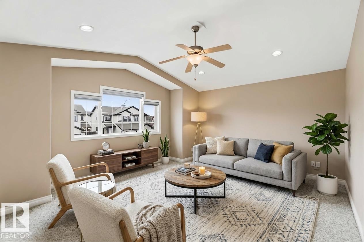 Carpeted living area featuring a vaulted ceiling with a ceiling fan, recessed lighting, and a triple window assembly - 16412 60 Street, Edmonton, AB - Indoor Photo Showing Living Room