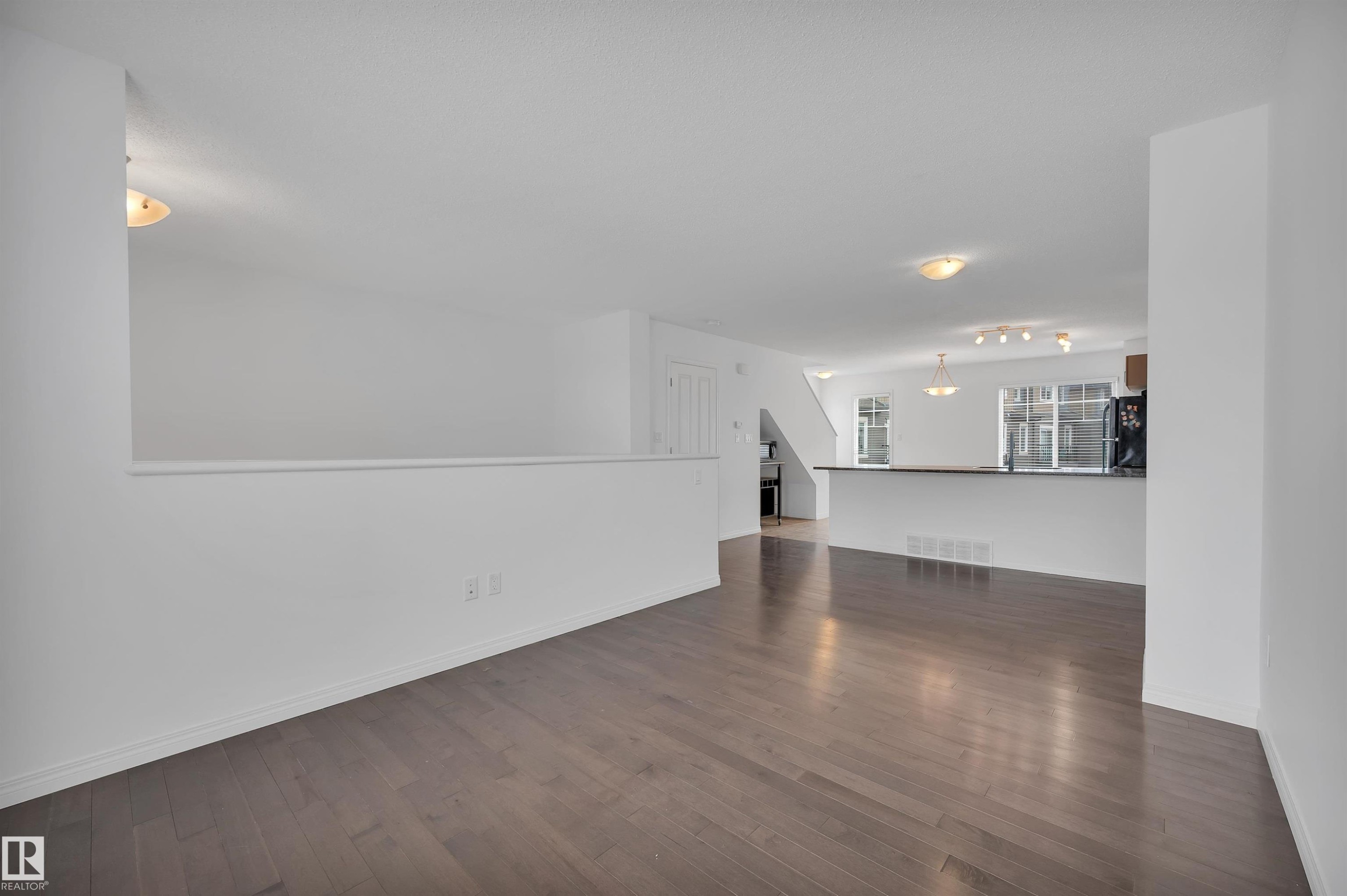 Open-concept living area featuring wood-finish flooring, white walls, and contemporary ceiling lighting - 13 1030 Chappelle Boulevard, Edmonton, AB - Indoor Photo Showing Other Room