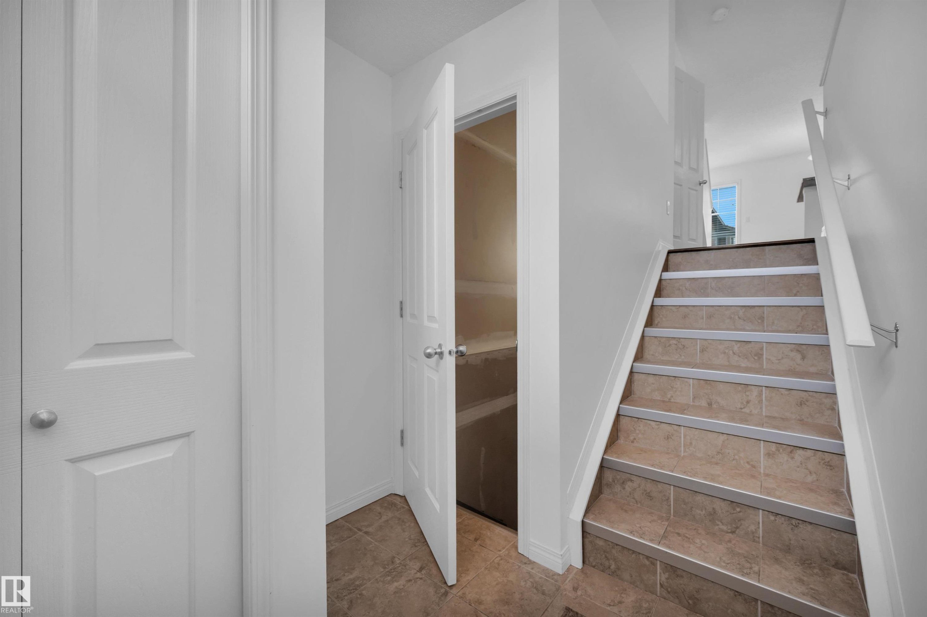 Tiled flooring extends from the entryway to the staircase, featuring a white handrail and white baseboards - 13 1030 Chappelle Boulevard, Edmonton, AB - Indoor Photo Showing Other Room