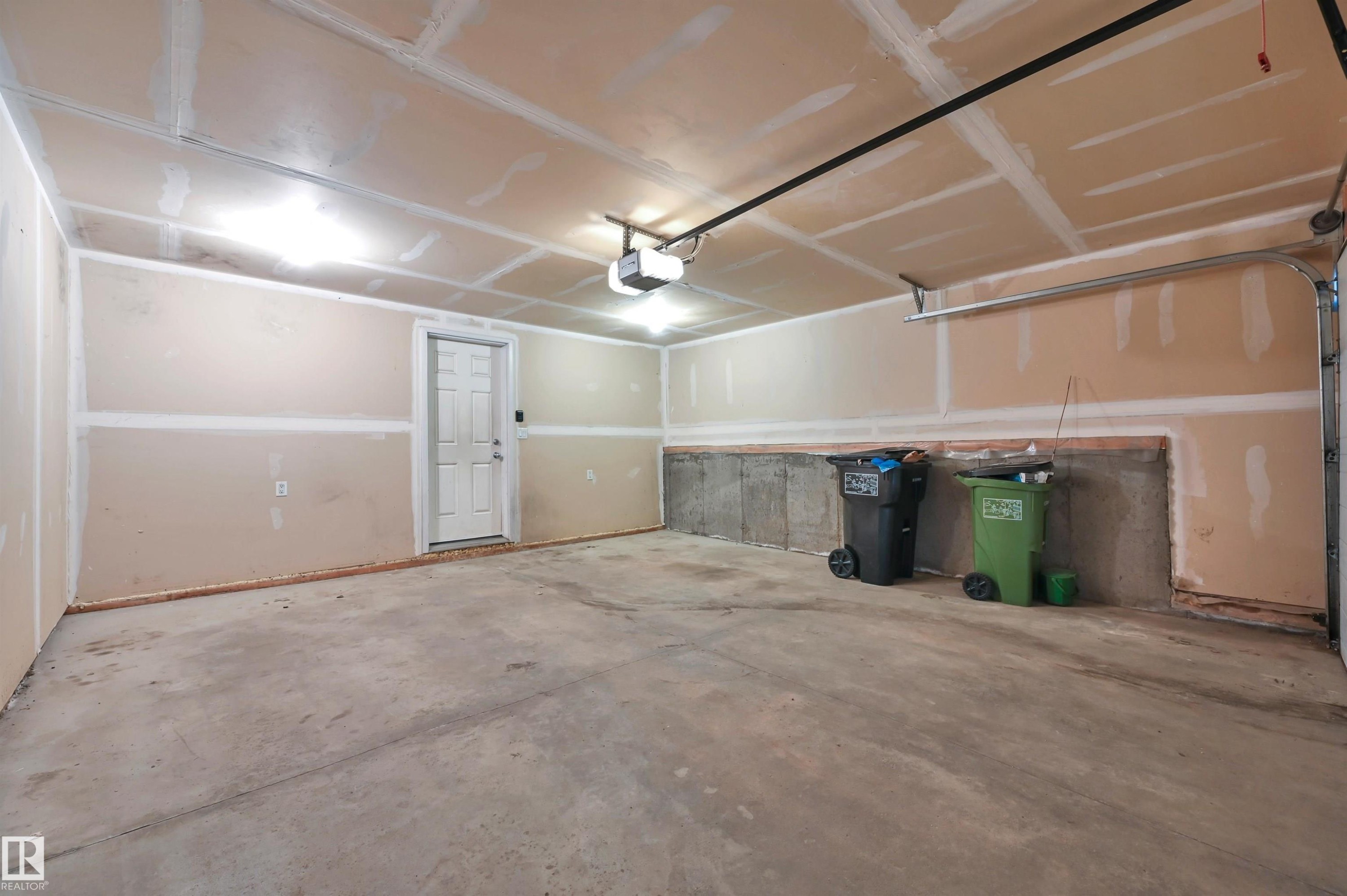 Spacious garage with exposed concrete flooring and unfinished drywall - 13 1030 Chappelle Boulevard, Edmonton, AB - Indoor Photo Showing Garage