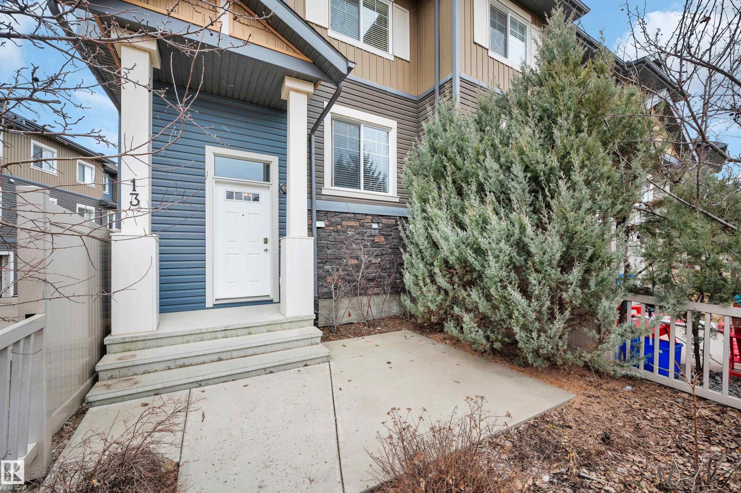 Exterior featuring blue horizontal siding, stone veneer accents, and white trim - 13 1030 Chappelle Boulevard, Edmonton, AB - Outdoor