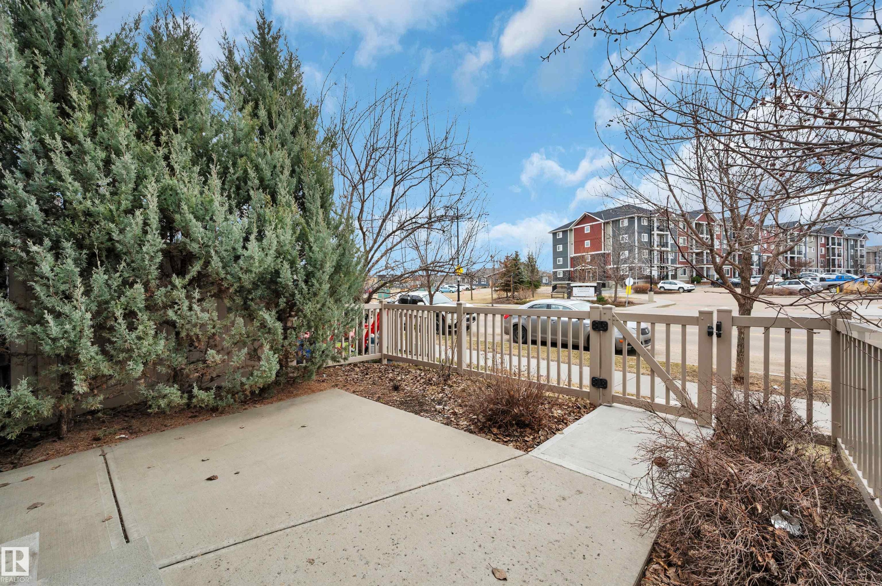 Concrete patio area featuring a slatted privacy fence with a gated entry - 13 1030 Chappelle Boulevard, Edmonton, AB - Outdoor