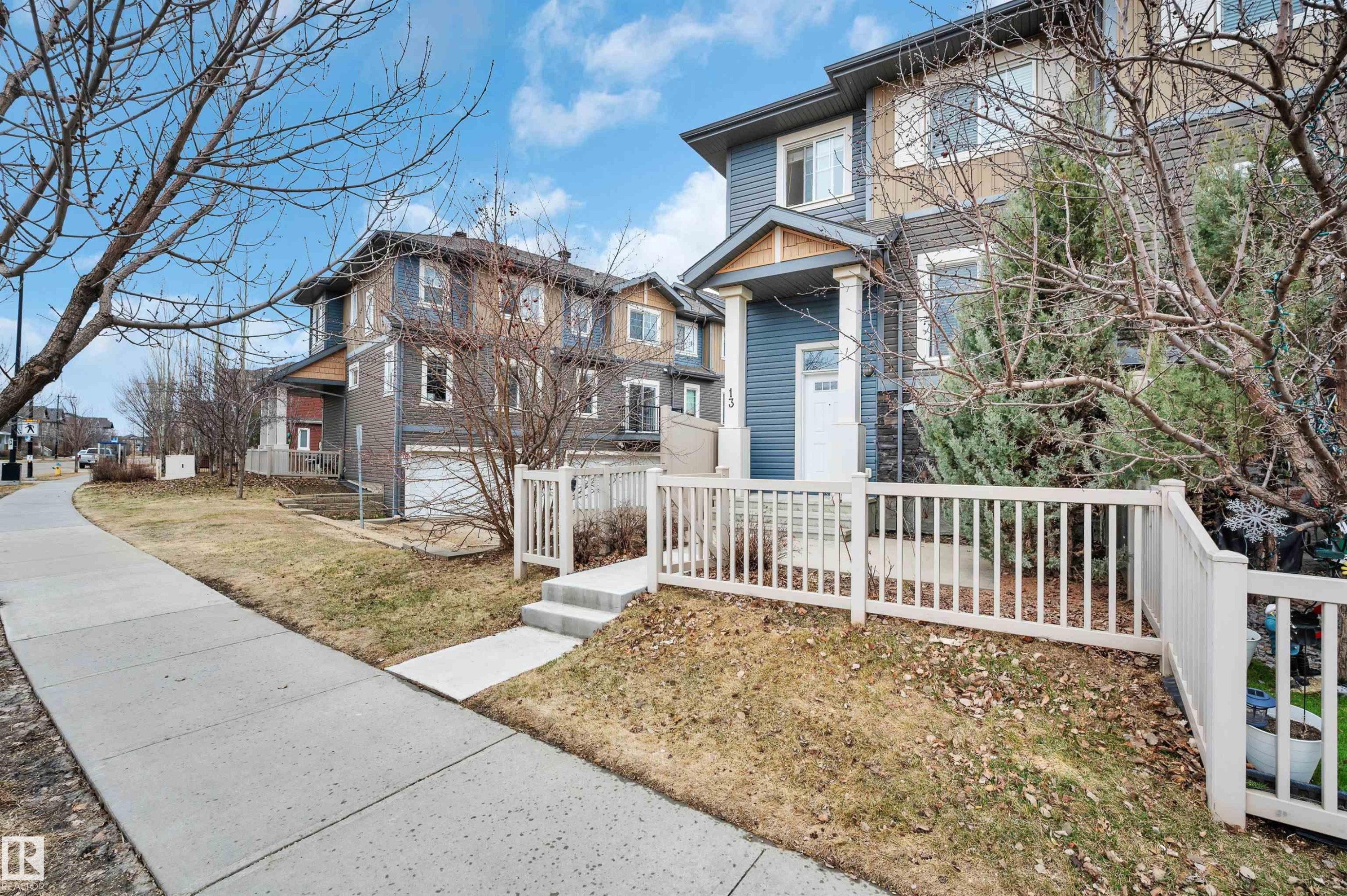 Two-story property featuring a blue siding exterior with stone accents and a white front entry door - 13 1030 Chappelle Boulevard, Edmonton, AB - Outdoor With Facade