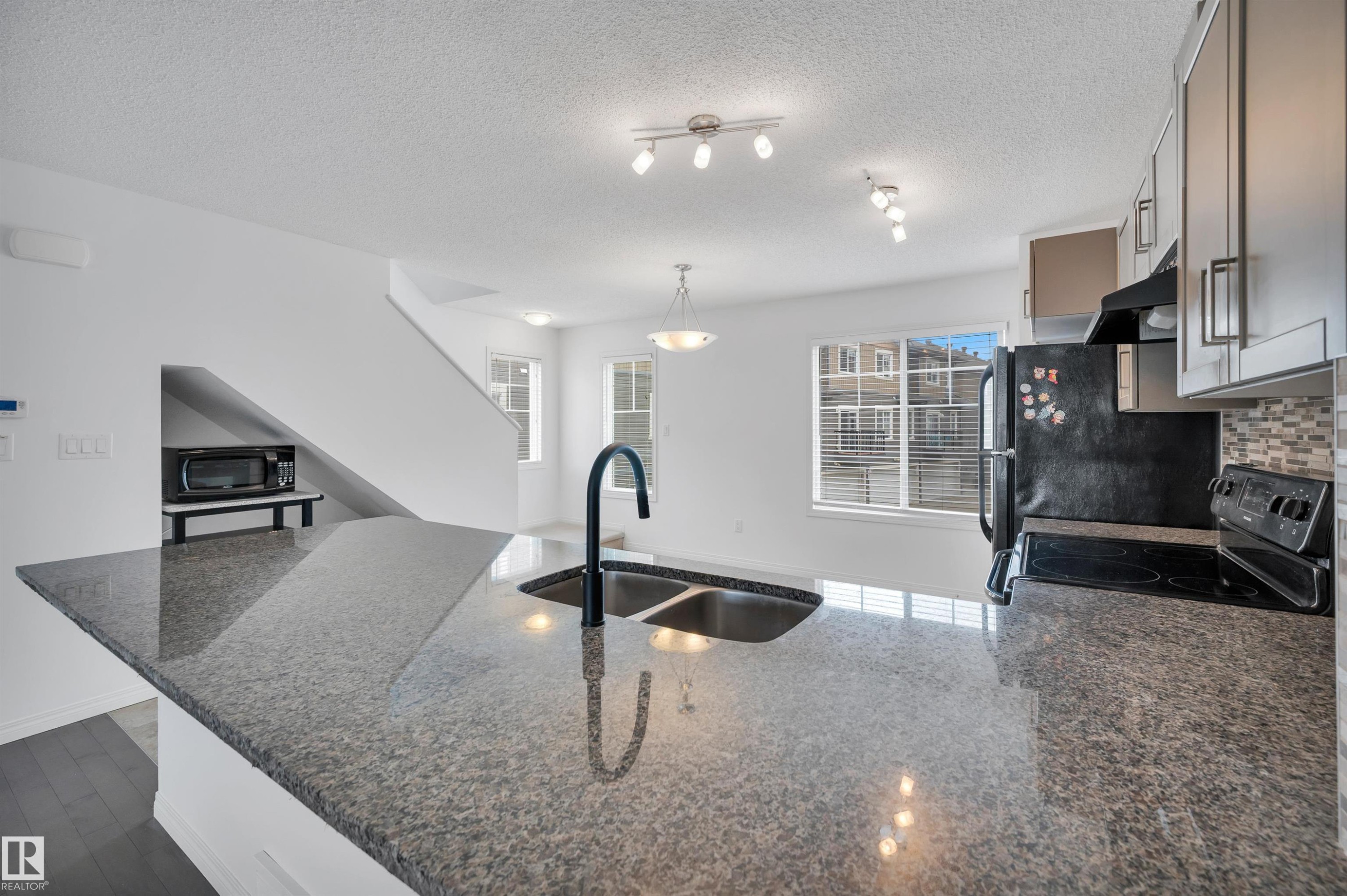 Kitchen island with a double basin sink and gooseneck faucet - 13 1030 Chappelle Boulevard, Edmonton, AB - Indoor Photo Showing Kitchen With Double Sink With Upgraded Kitchen