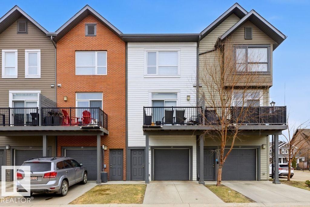 Multi-level townhouse exterior featuring a brick facade, white siding, and horizontal paneling - 18, 2560 Pegasus Boulevard, Edmonton, AB - Outdoor With Facade