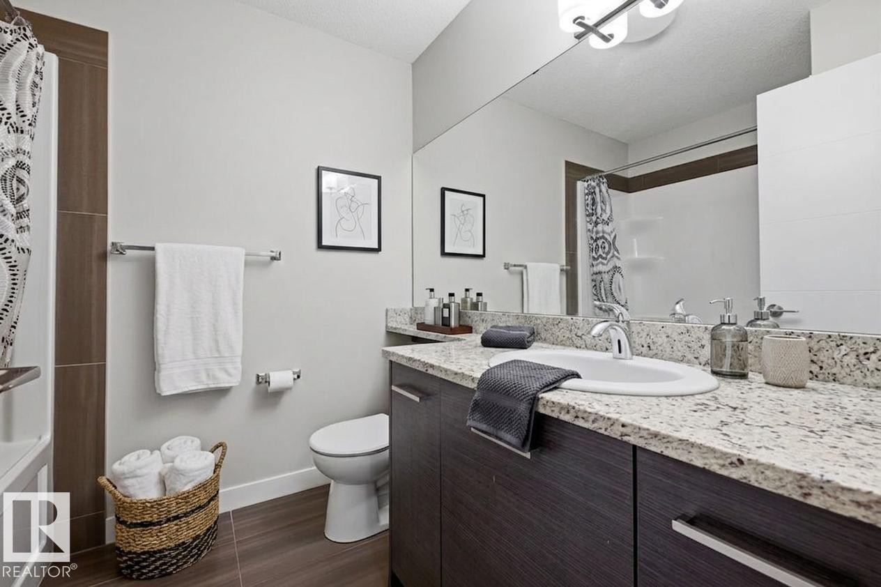 Bathroom featuring a dark wood-finish vanity with a granite countertop and an undermount sink - 18, 2560 Pegasus Boulevard, Edmonton, AB - Indoor Photo Showing Bathroom
