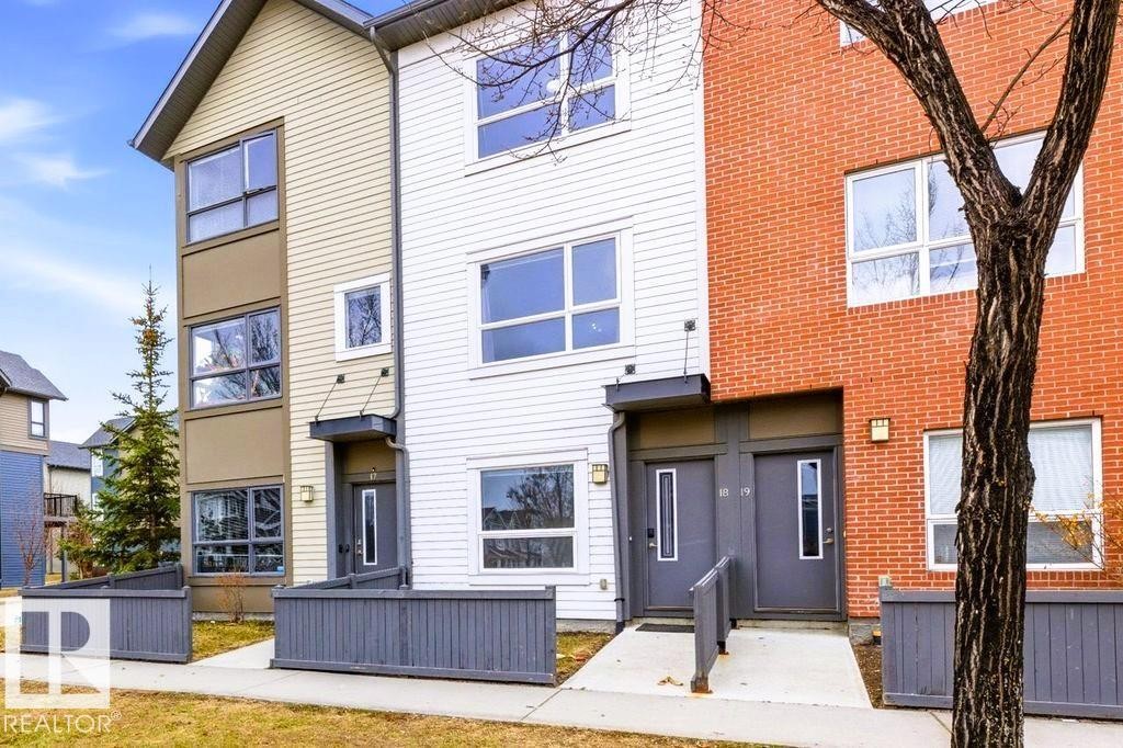 Multi-level townhome exterior featuring an entrance with an awning and a grey fence - 18, 2560 Pegasus Boulevard, Edmonton, AB - Outdoor With Facade