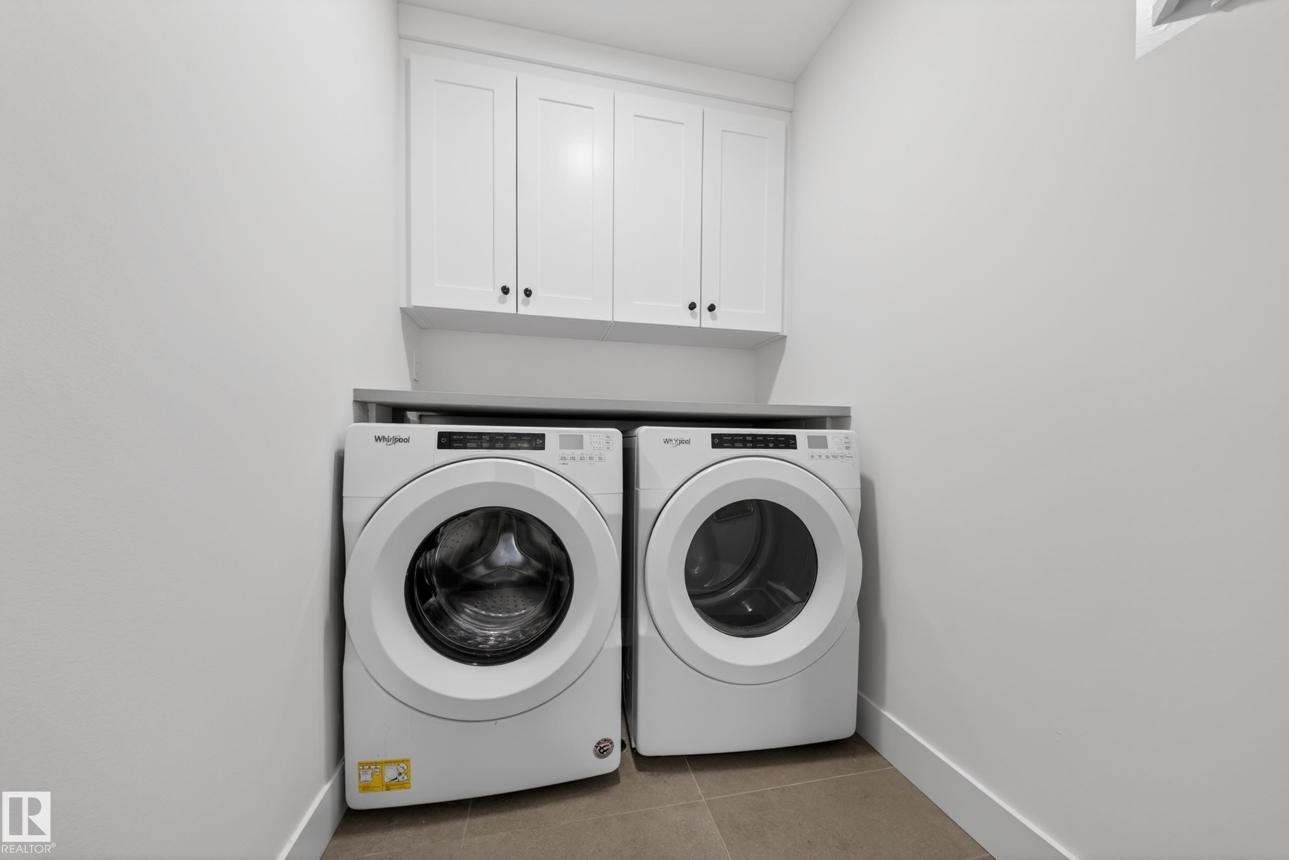 Dedicated laundry space featuring white shaker-style cabinetry, a gray countertop, and tile flooring - 7414 Chivers Crescent Sw, Edmonton, AB - Indoor Photo Showing Laundry Room