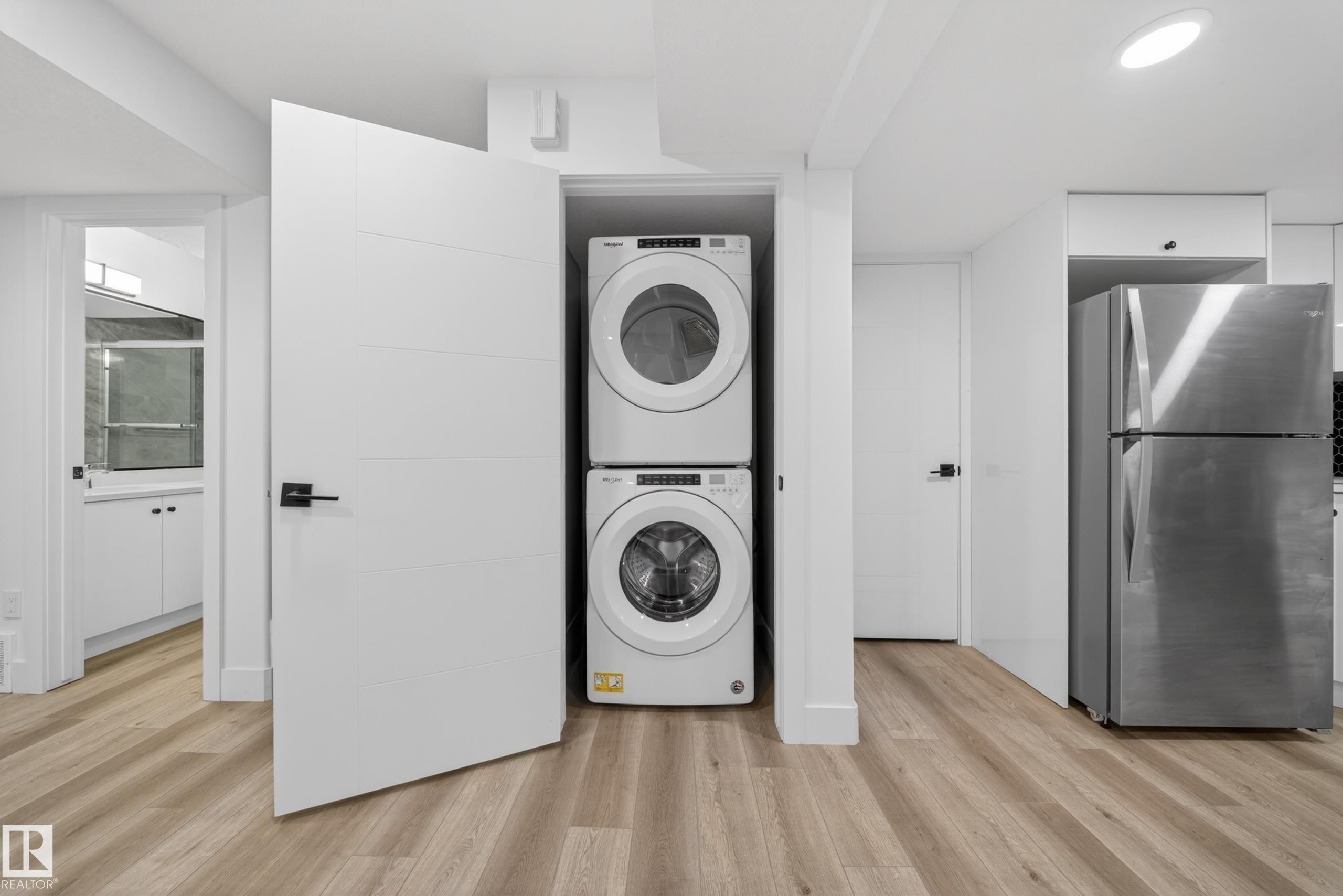 Integrated laundry closet with stacked appliances - 7414 Chivers Crescent Sw, Edmonton, AB - Indoor Photo Showing Laundry Room