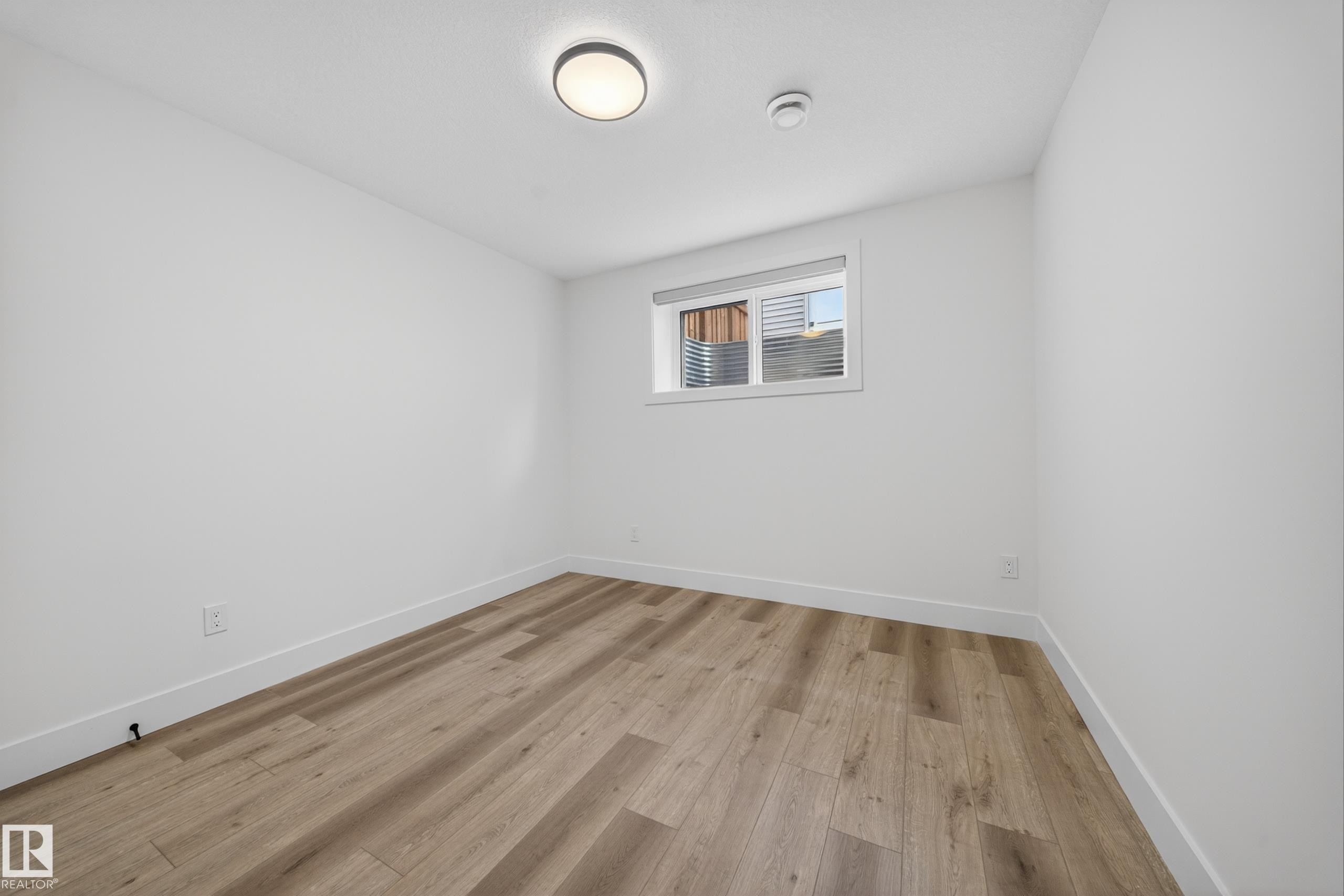 Room featuring wood-finish flooring, white walls, and bright white trim - 7414 Chivers Crescent Sw, Edmonton, AB - Indoor Photo Showing Other Room