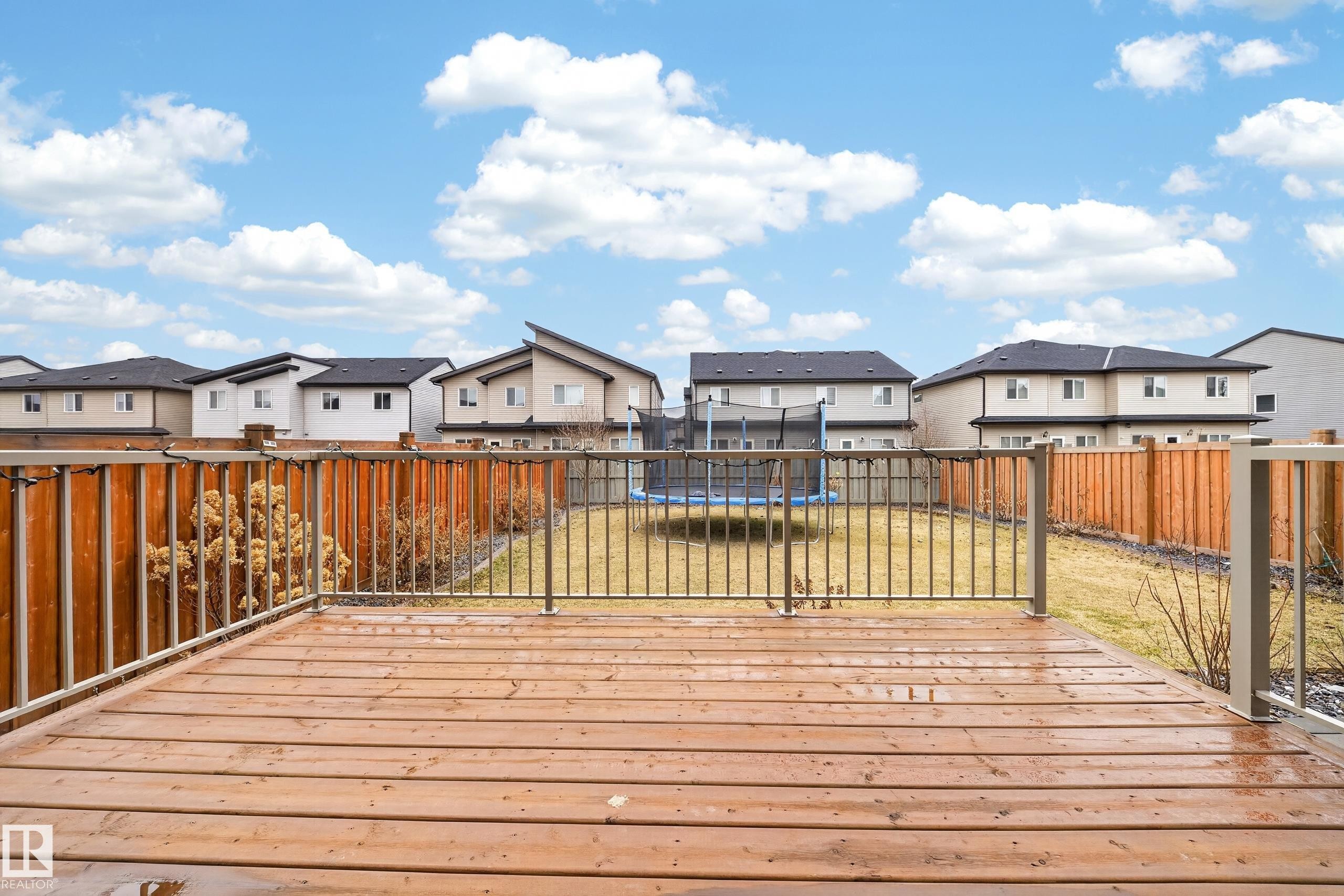 Expansive wood deck with metal railings overlooking a backyard with a grass lawn and wood fencing - 7414 Chivers Crescent Sw, Edmonton, AB - Outdoor With Deck Patio Veranda With Exterior
