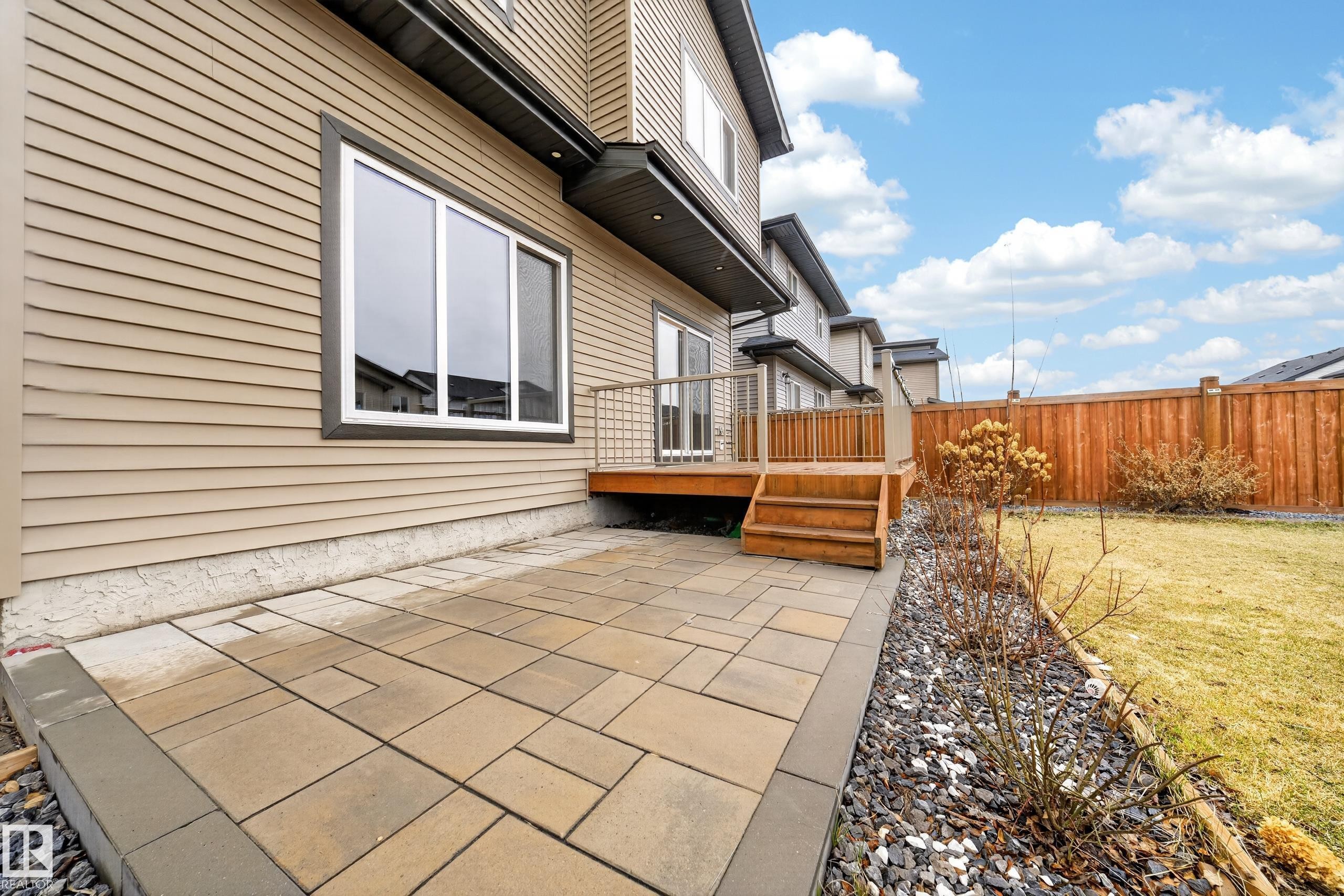 Paved patio and landscaped garden bed with decorative rock, featuring a wood deck with steps - 7414 Chivers Crescent Sw, Edmonton, AB - Outdoor With Deck Patio Veranda With Exterior