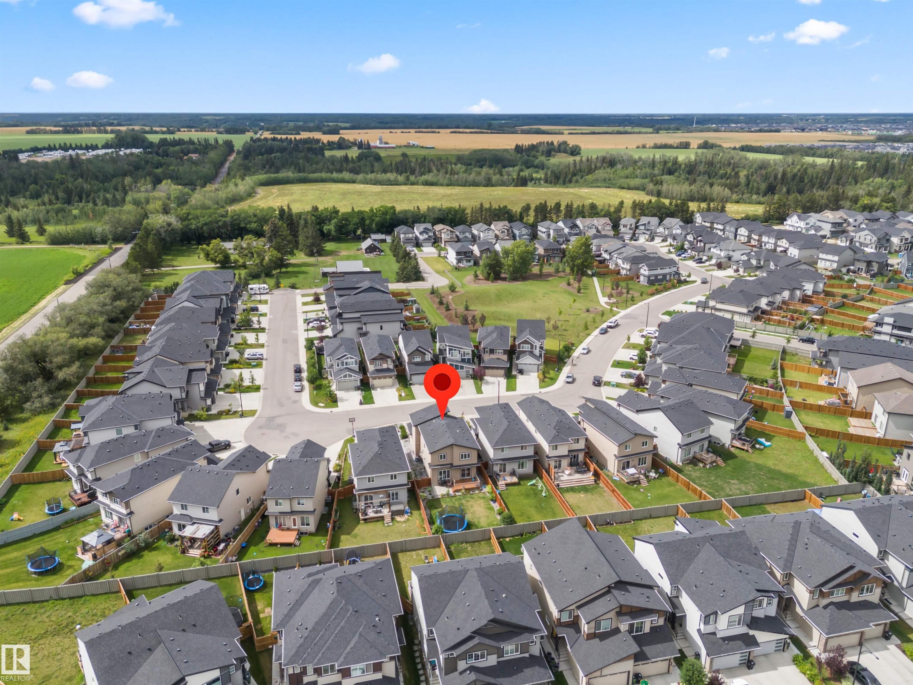 Aerial perspective showcasing a residential neighborhood with detached homes, surrounded by green spaces and agricultural fields - 7414 Chivers Crescent Sw, Edmonton, AB - Outdoor With View