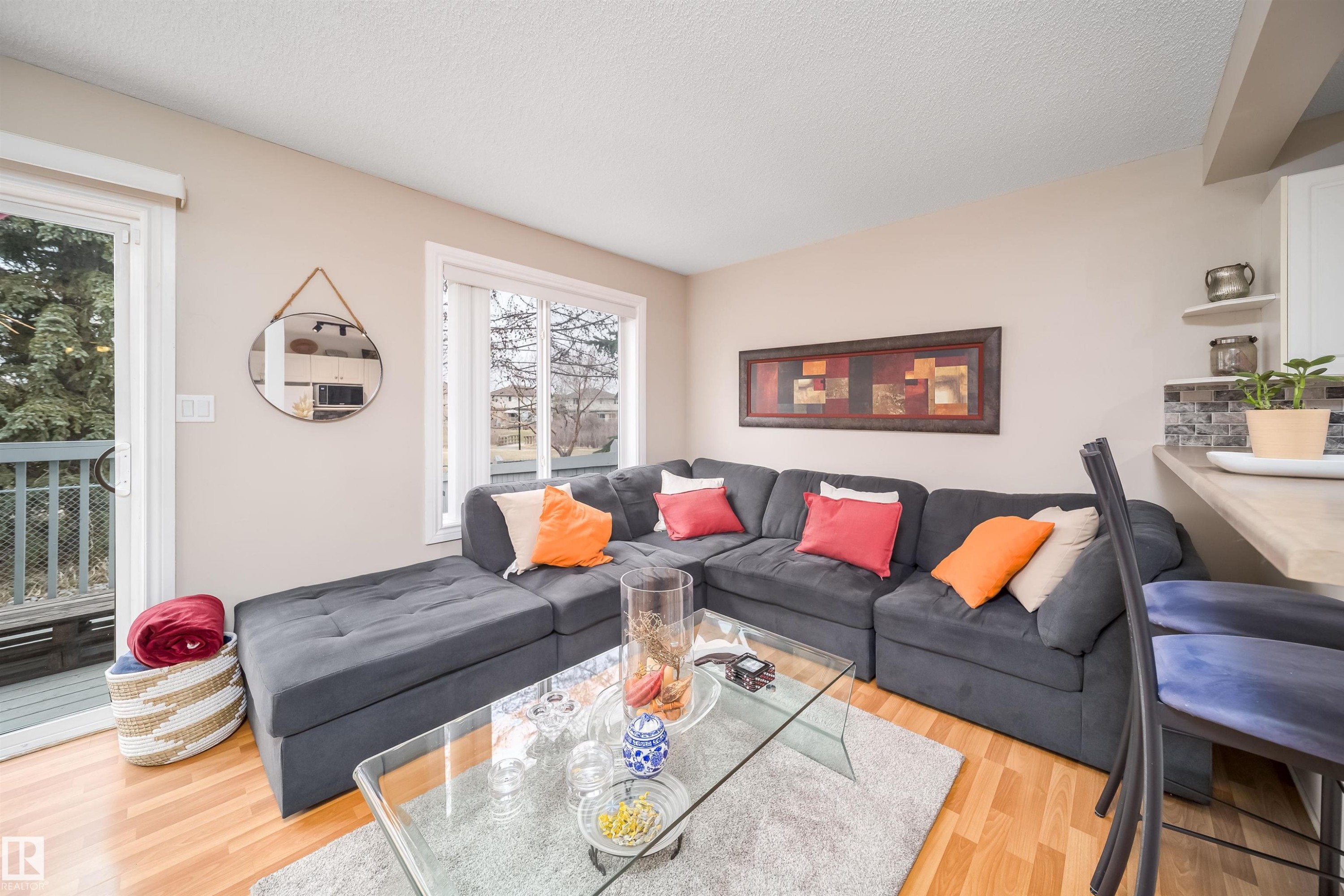 Open-concept living space featuring wood-finish flooring, a large window, and a sliding glass door to an outdoor deck - 50 14603 Miller Boulevard, Edmonton, AB
