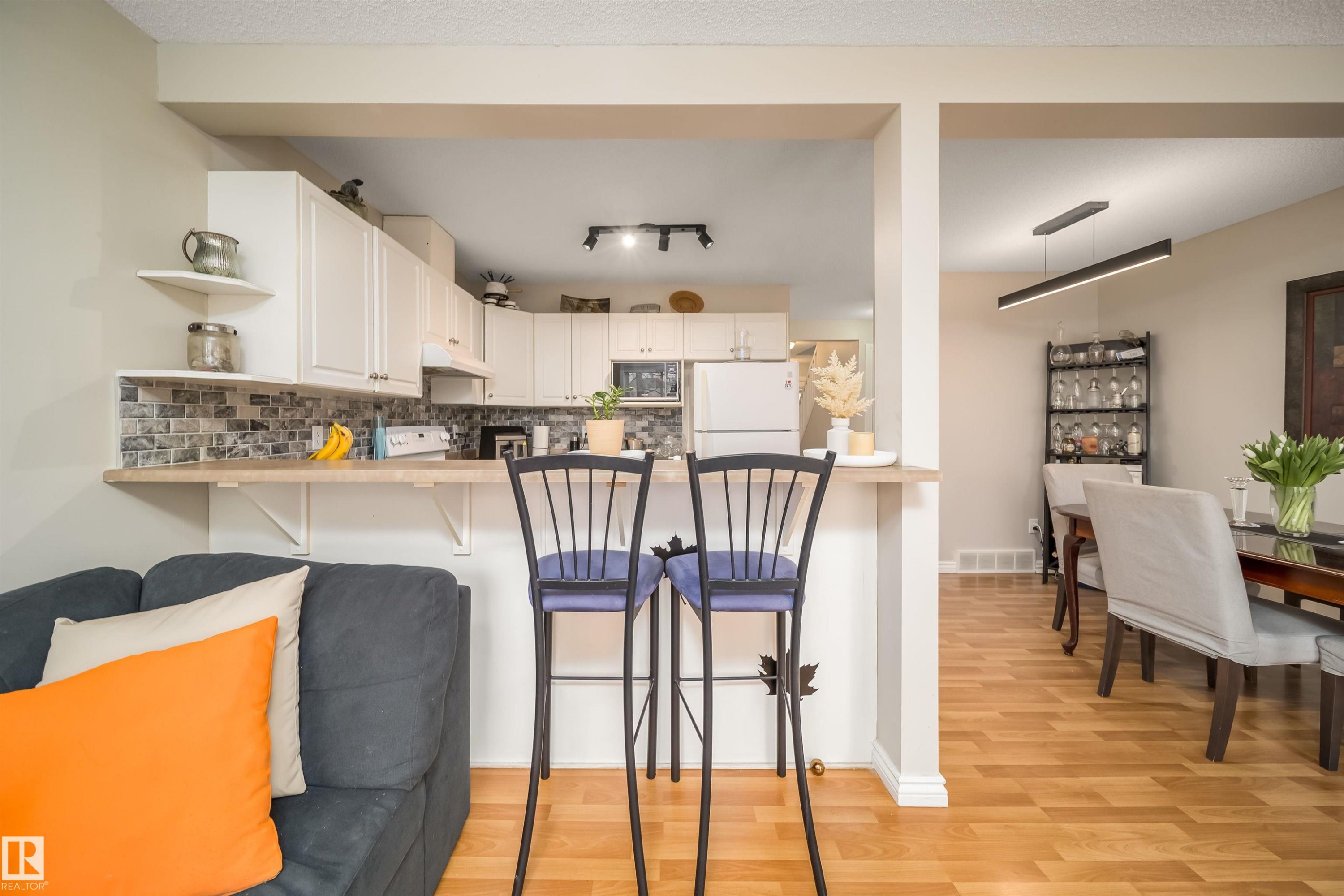 Kitchen with white cabinetry, tile backsplash, and a breakfast bar - 50 14603 Miller Boulevard, Edmonton, AB