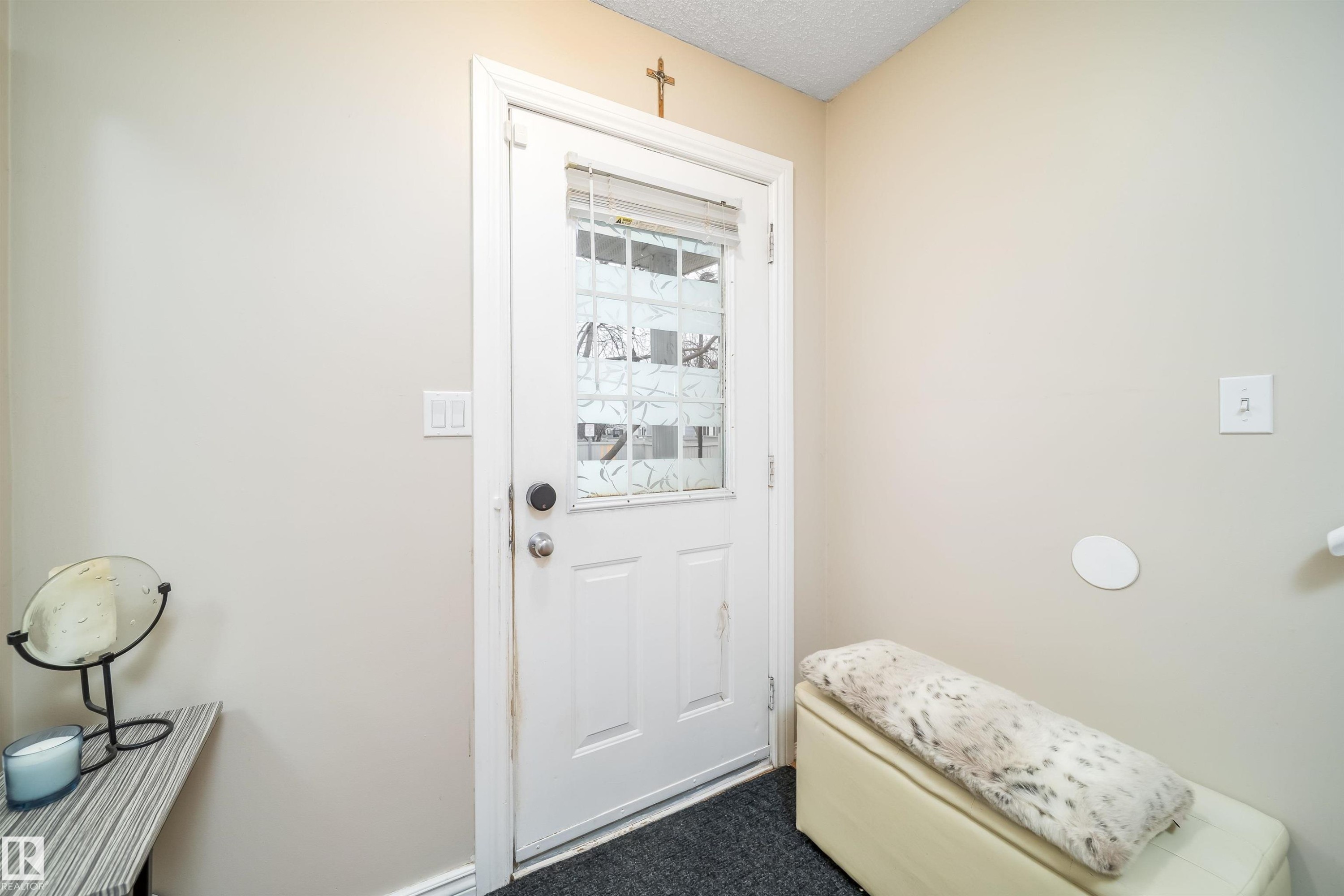 Entry door with decorative glass inserts, white trim, and a dark floor mat - 50 14603 Miller Boulevard, Edmonton, AB
