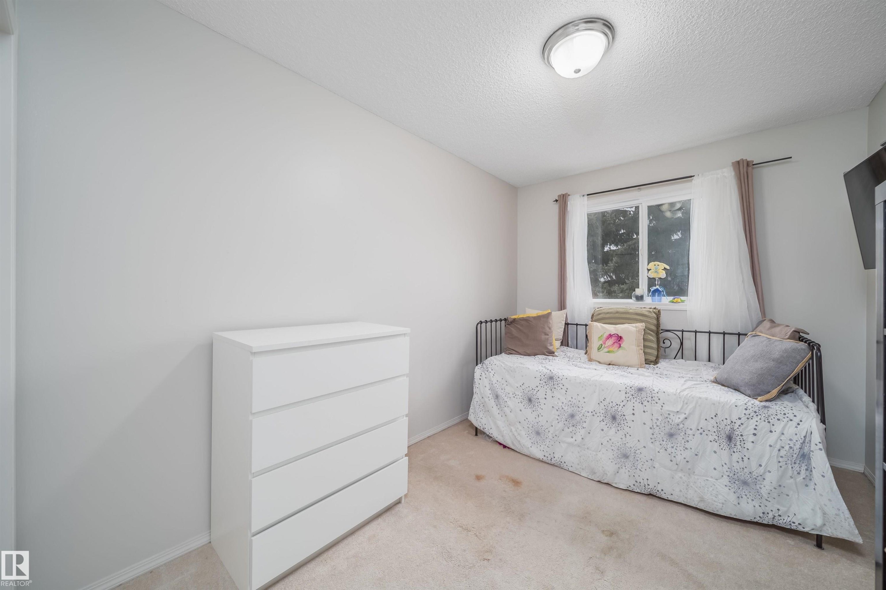 Neutral-toned room with light-colored carpeting and a single window - 50 14603 Miller Boulevard, Edmonton, AB