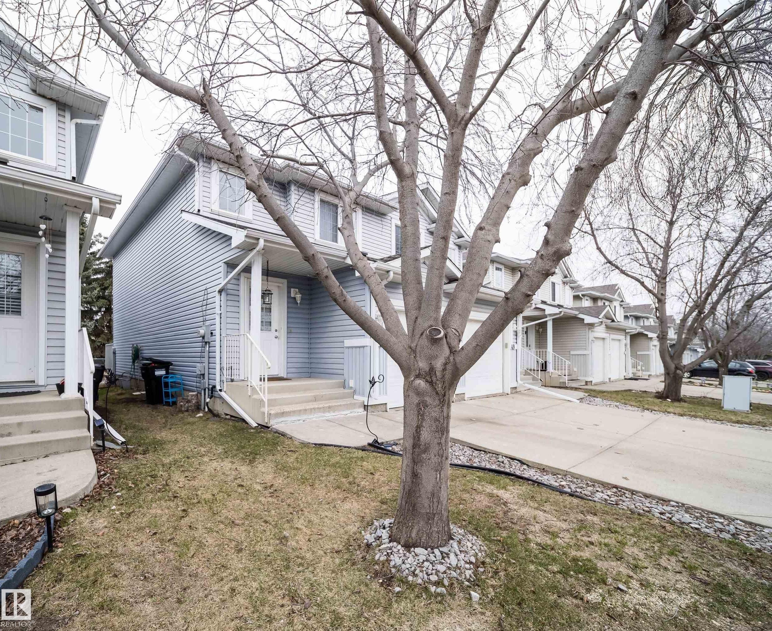 Exterior featuring light blue vinyl siding and a white front door with a glass insert - 50 14603 Miller Boulevard, Edmonton, AB