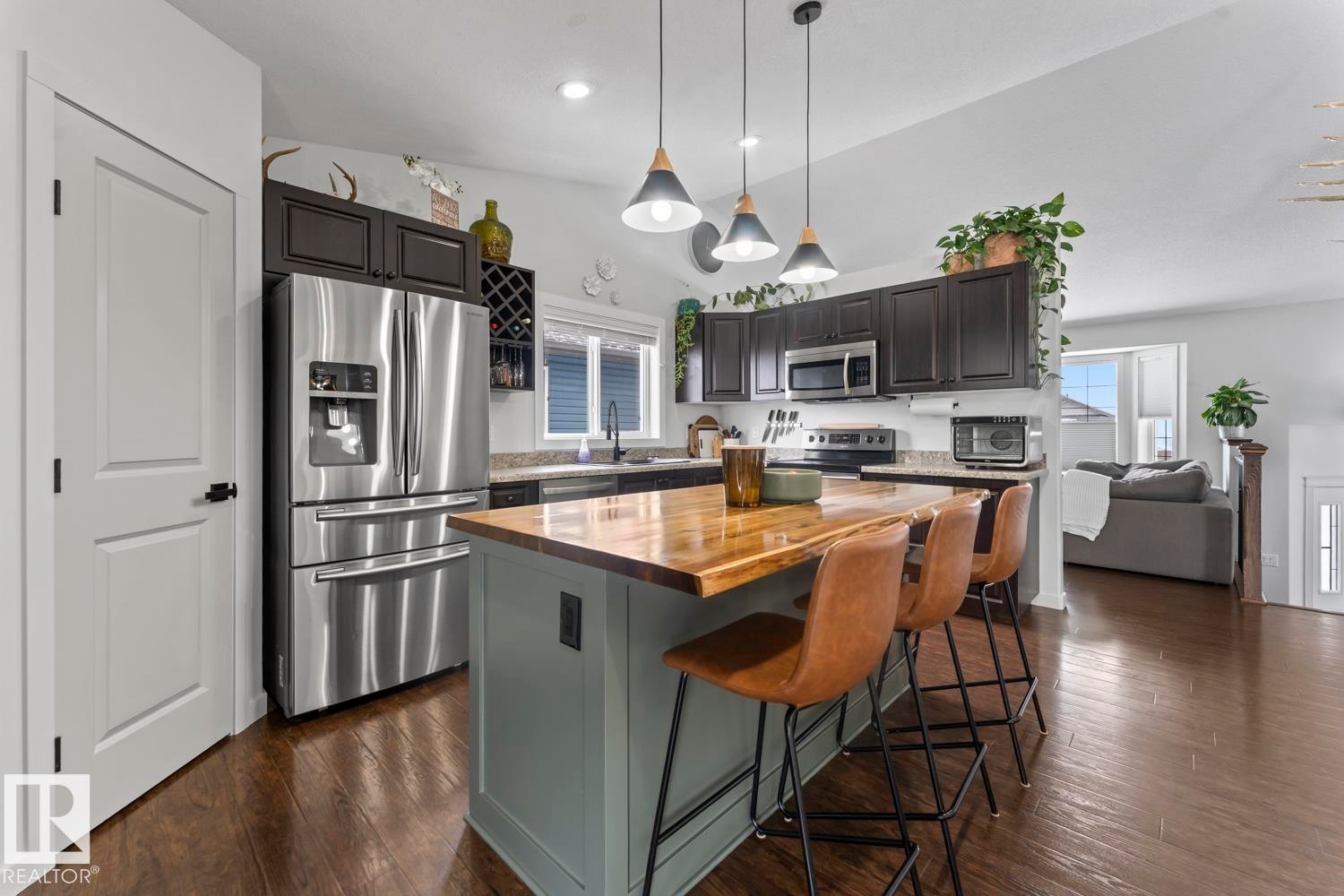 Kitchen featuring dark cabinetry, stainless steel appliances, and a central island with a wood-finish countertop - 4926 58 Ave, Cold Lake, AB - Indoor Photo Showing Kitchen With Upgraded Kitchen