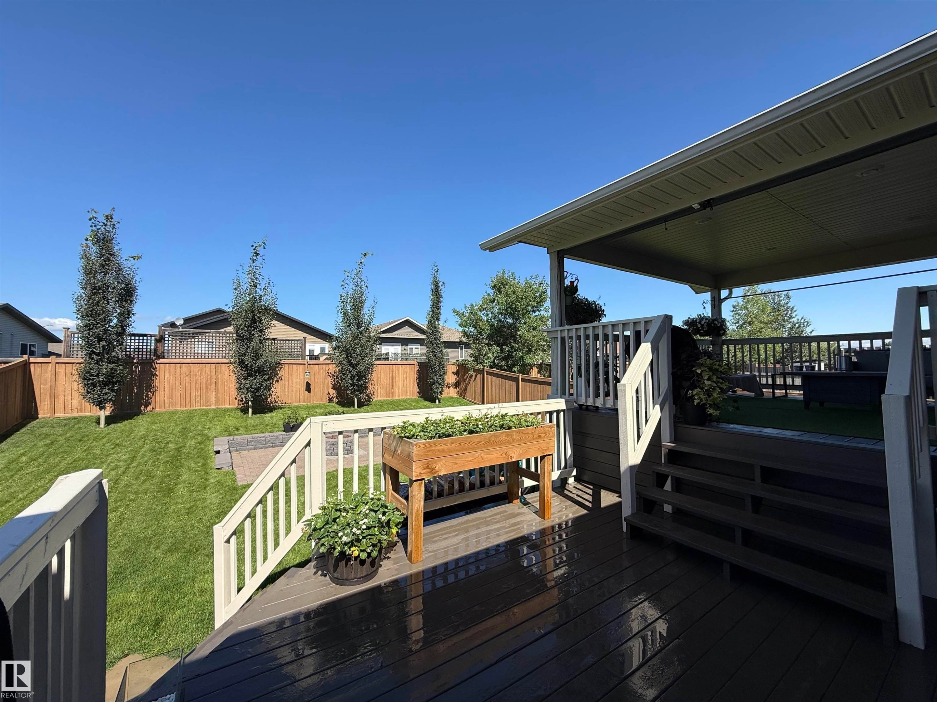 Multi-level deck featuring a covered upper platform with artificial turf, a lower wood-finish deck, and white railings - 4926 58 Ave, Cold Lake, AB - Outdoor With Deck Patio Veranda