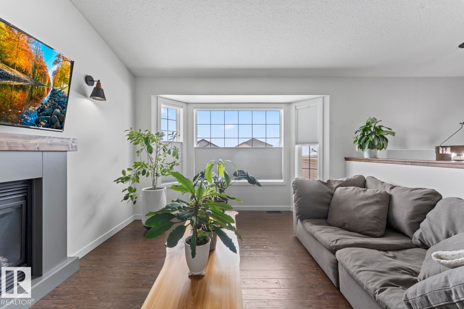Living area featuring wood-finish flooring and a bay window - 4926 58 Ave, Cold Lake, AB - Indoor Photo Showing Living Room With Fireplace