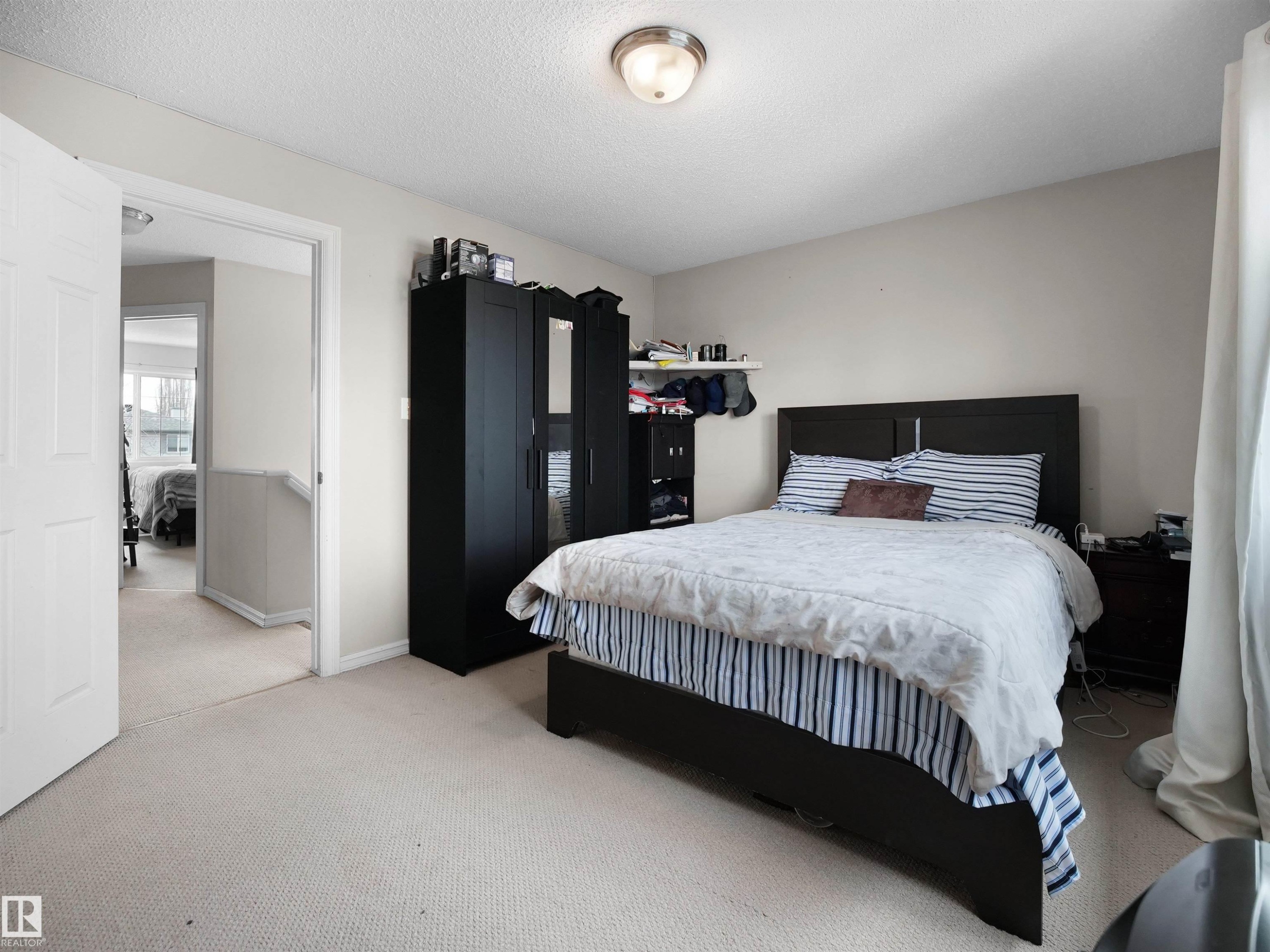 Carpeted bedroom with a built-in wall shelf and a ceiling-mounted light fixture - 21379 89 Avenue Nw, Edmonton, AB - Indoor Photo Showing Bedroom