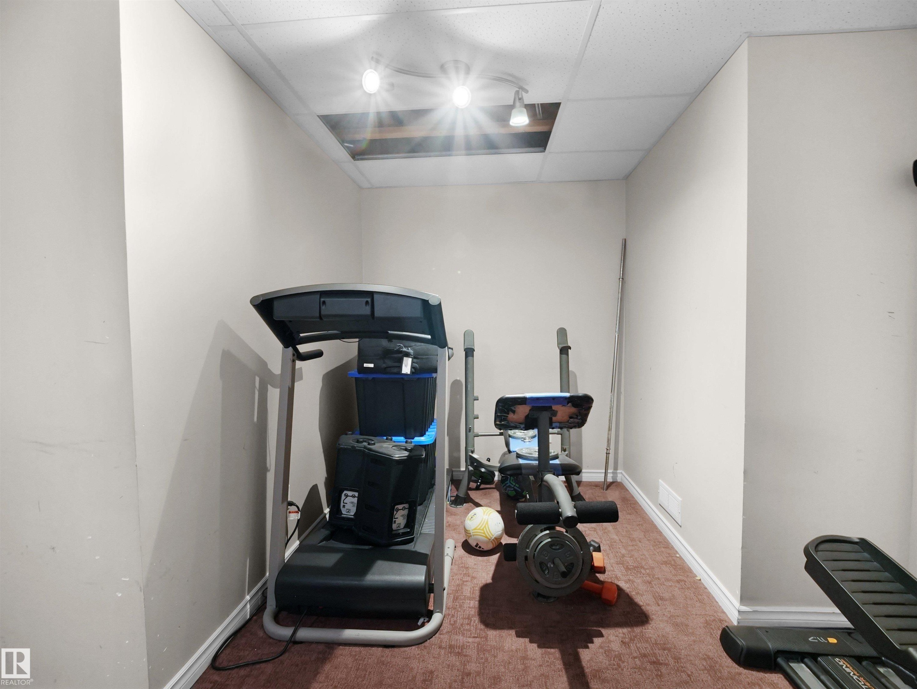 Recessed lighting fixtures illuminate a room featuring light-colored walls and a drop ceiling - 21379 89 Avenue Nw, Edmonton, AB - Indoor Photo Showing Gym Room