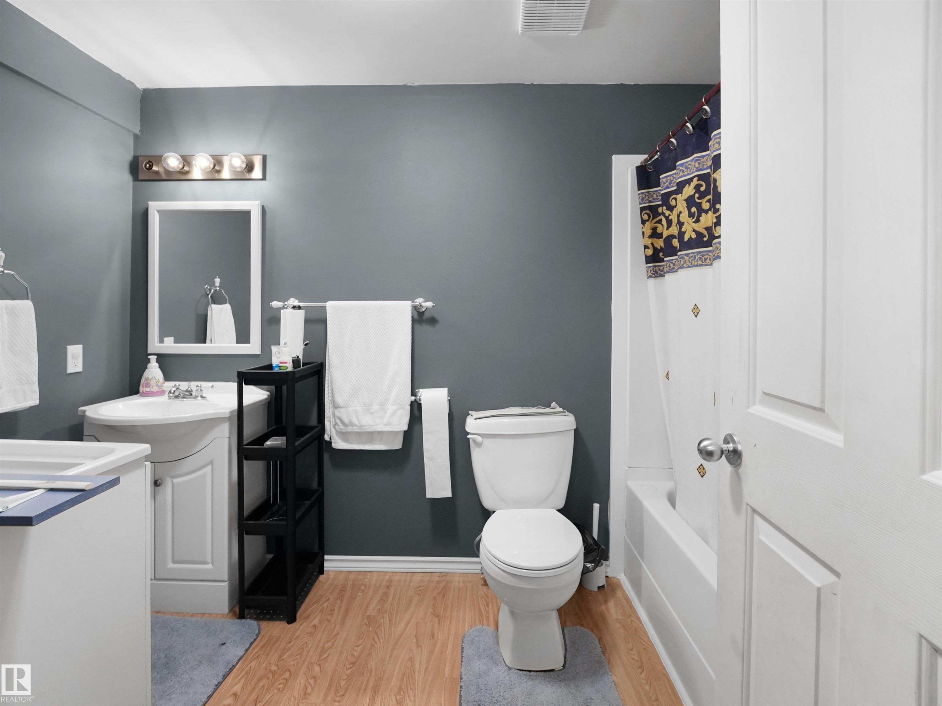White vanity with integrated sink and chrome faucet, illuminated by a four-bulb vanity light - 21379 89 Avenue Nw, Edmonton, AB - Indoor Photo Showing Bathroom