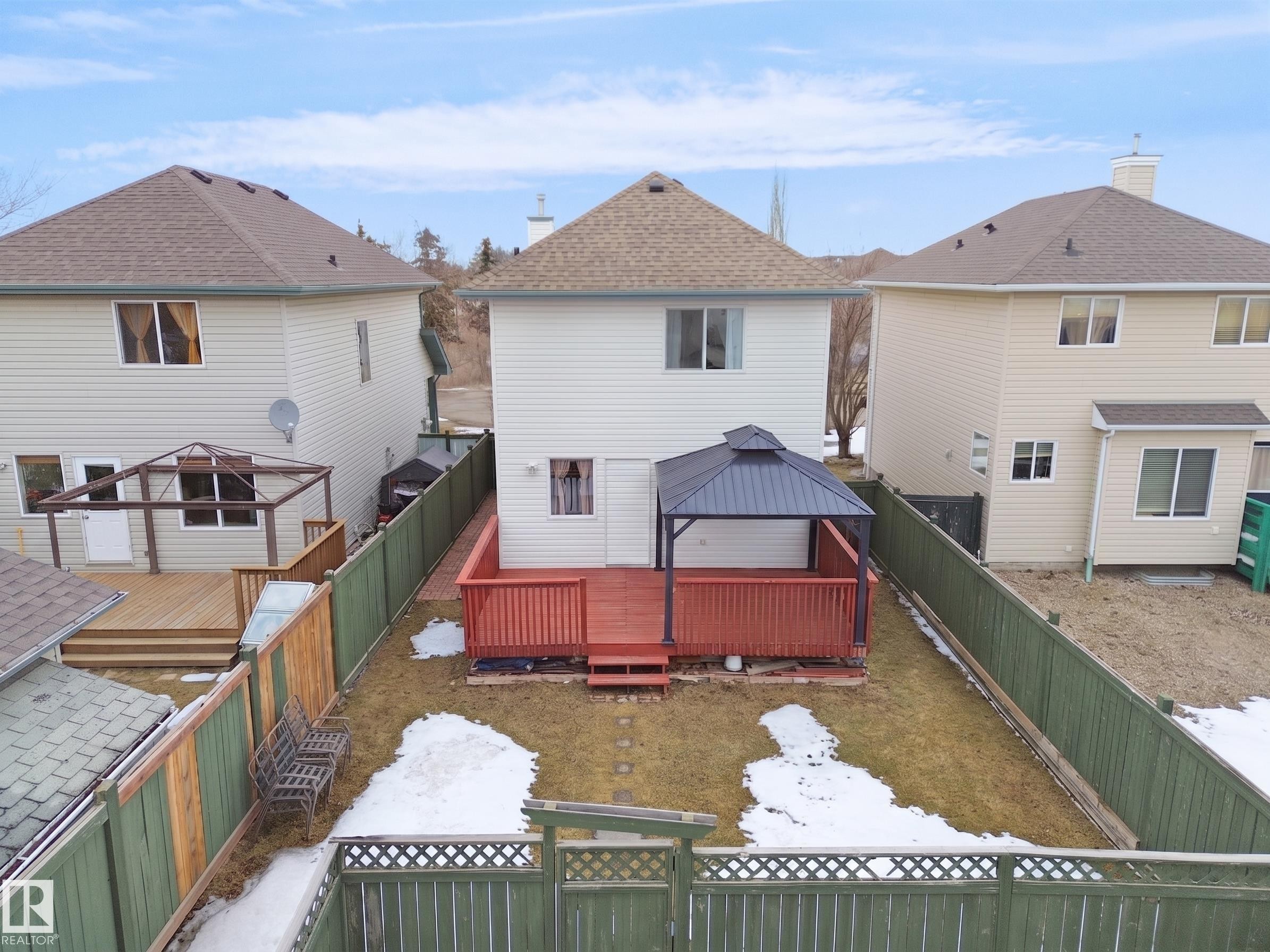 Expansive backyard featuring a red-stained wooden deck, a dark-roofed gazebo, and a green privacy fence - 21379 89 Avenue Nw, Edmonton, AB - Outdoor With Deck Patio Veranda With Exterior
