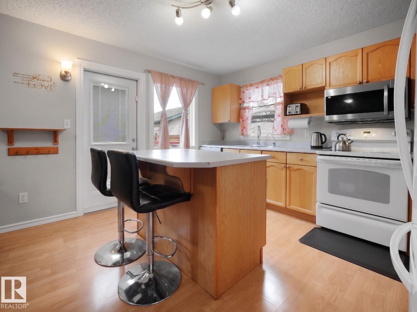 Kitchen featuring light wood-finish cabinetry, white countertops, and wood-finish flooring - 21379 89 Avenue Nw, Edmonton, AB - Indoor Photo Showing Kitchen