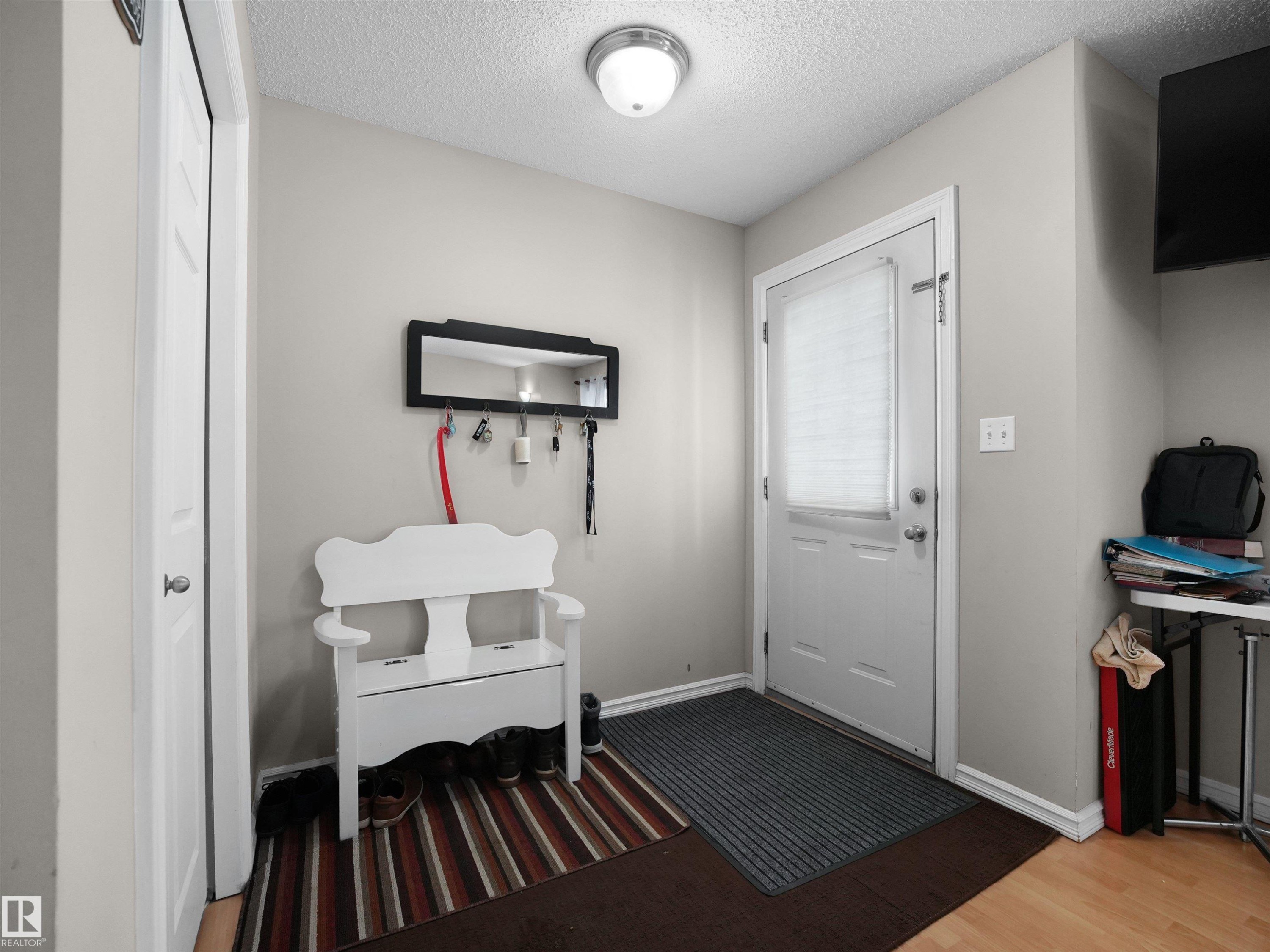 Entryway featuring light neutral wall paint, a white front door with a frosted glass insert, and wood-finish flooring - 21379 89 Avenue Nw, Edmonton, AB - Indoor Photo Showing Other Room