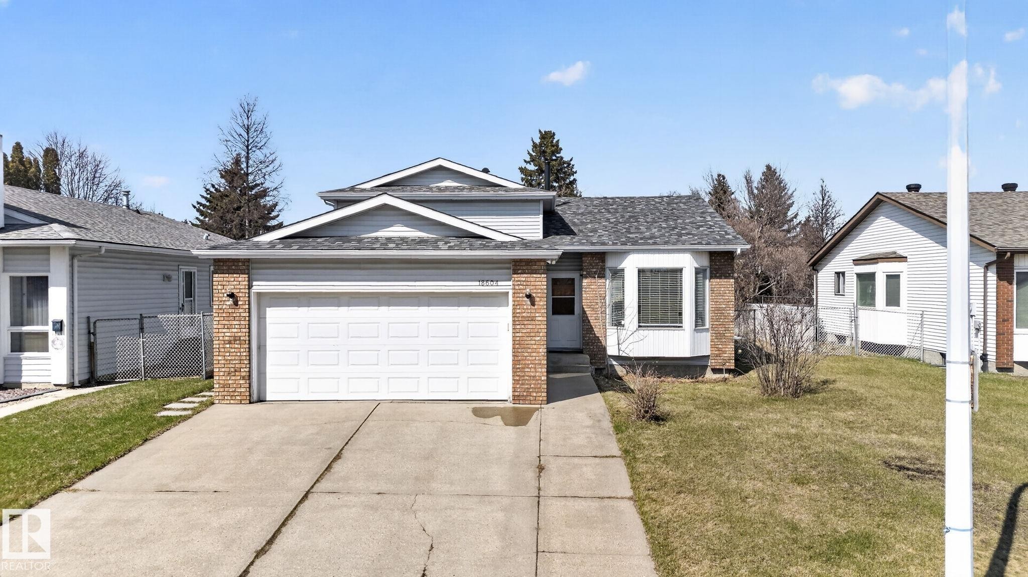 Split-level residence featuring a two-car garage, brick accents, and a bay window - 18604 97A Avenue, Edmonton, AB - Outdoor With Facade