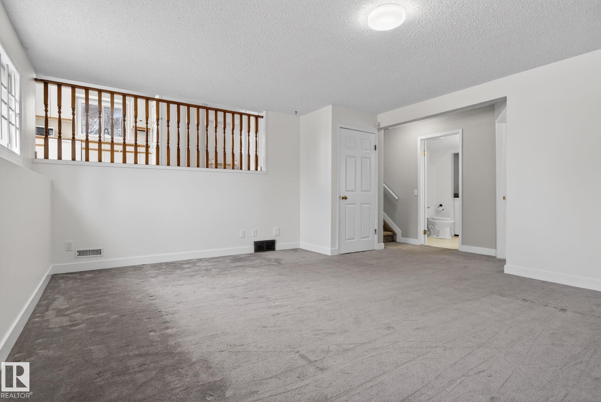 Carpeted room with a partial height wall featuring wood balusters and a white painted railing - 18604 97A Avenue, Edmonton, AB - Indoor Photo Showing Other Room