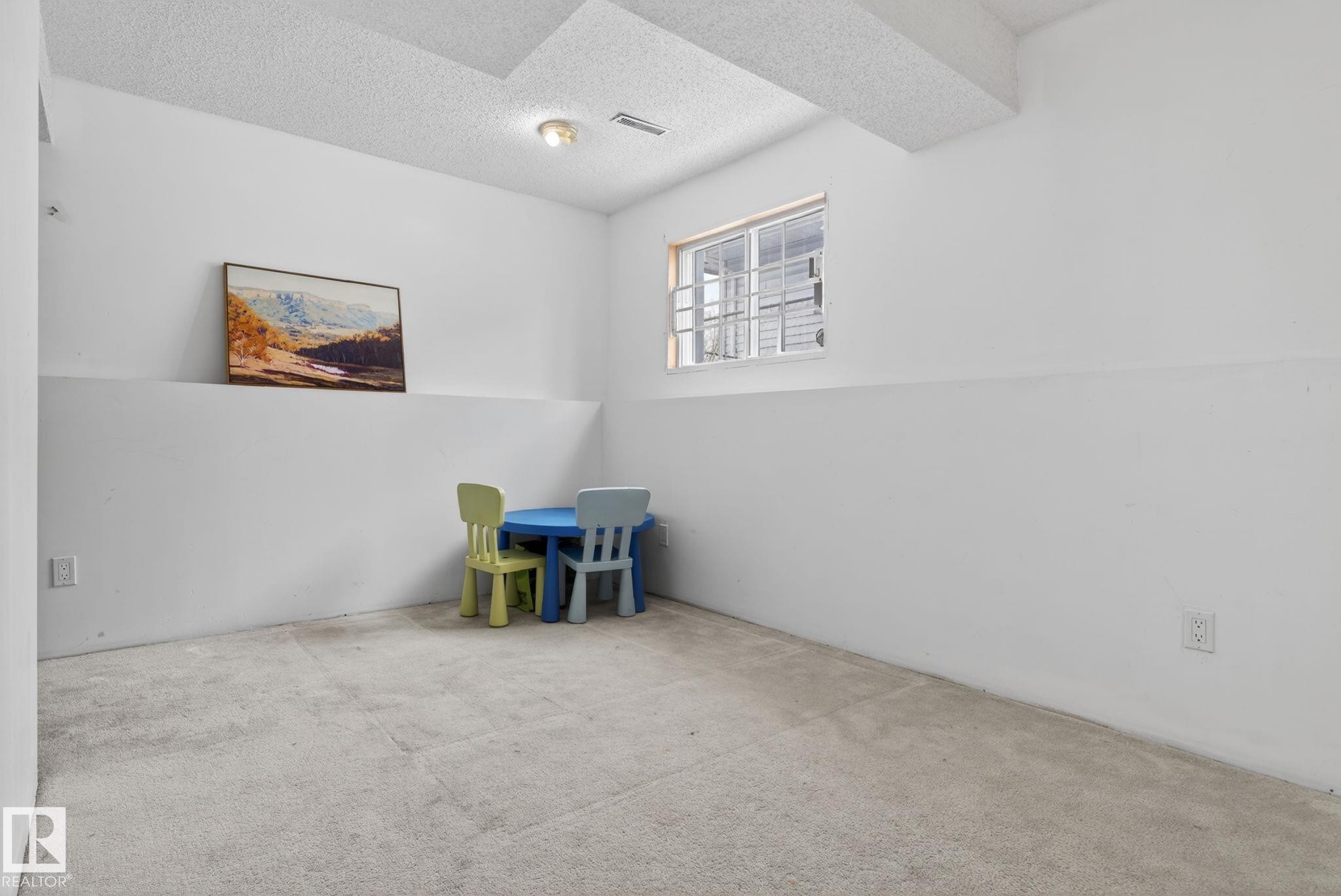 Carpeted room featuring a drop ceiling, white painted walls, and a single window with grilles - 18604 97A Avenue, Edmonton, AB - Indoor Photo Showing Other Room