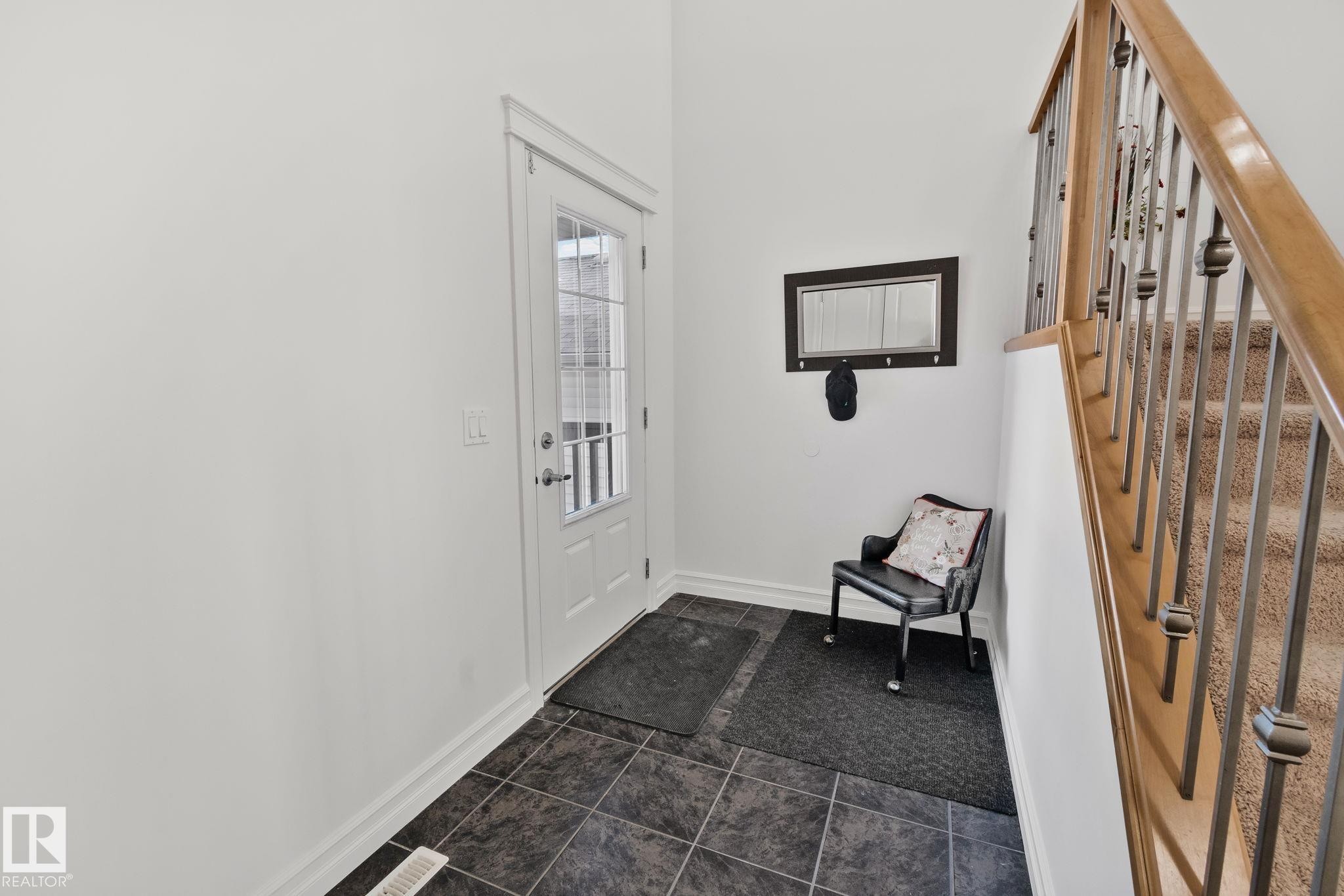 The entrance features tile flooring, a white door with glass panels, and a staircase with a wooden handrail and metal spindles - 1115 61 Street, Edmonton, AB - Indoor Photo Showing Other Room