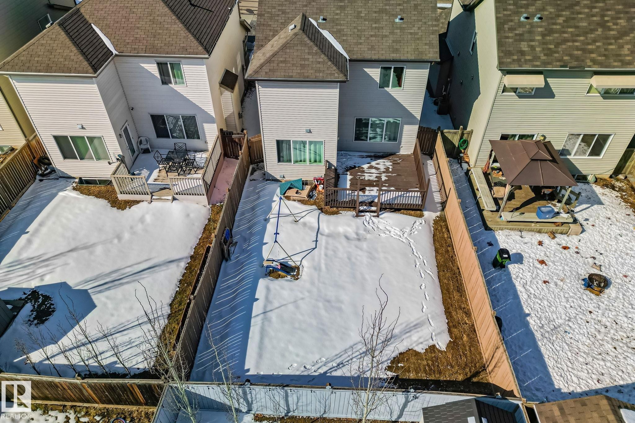 The property features a fenced yard with a deck and swing set - 1115 61 Street, Edmonton, AB - Outdoor