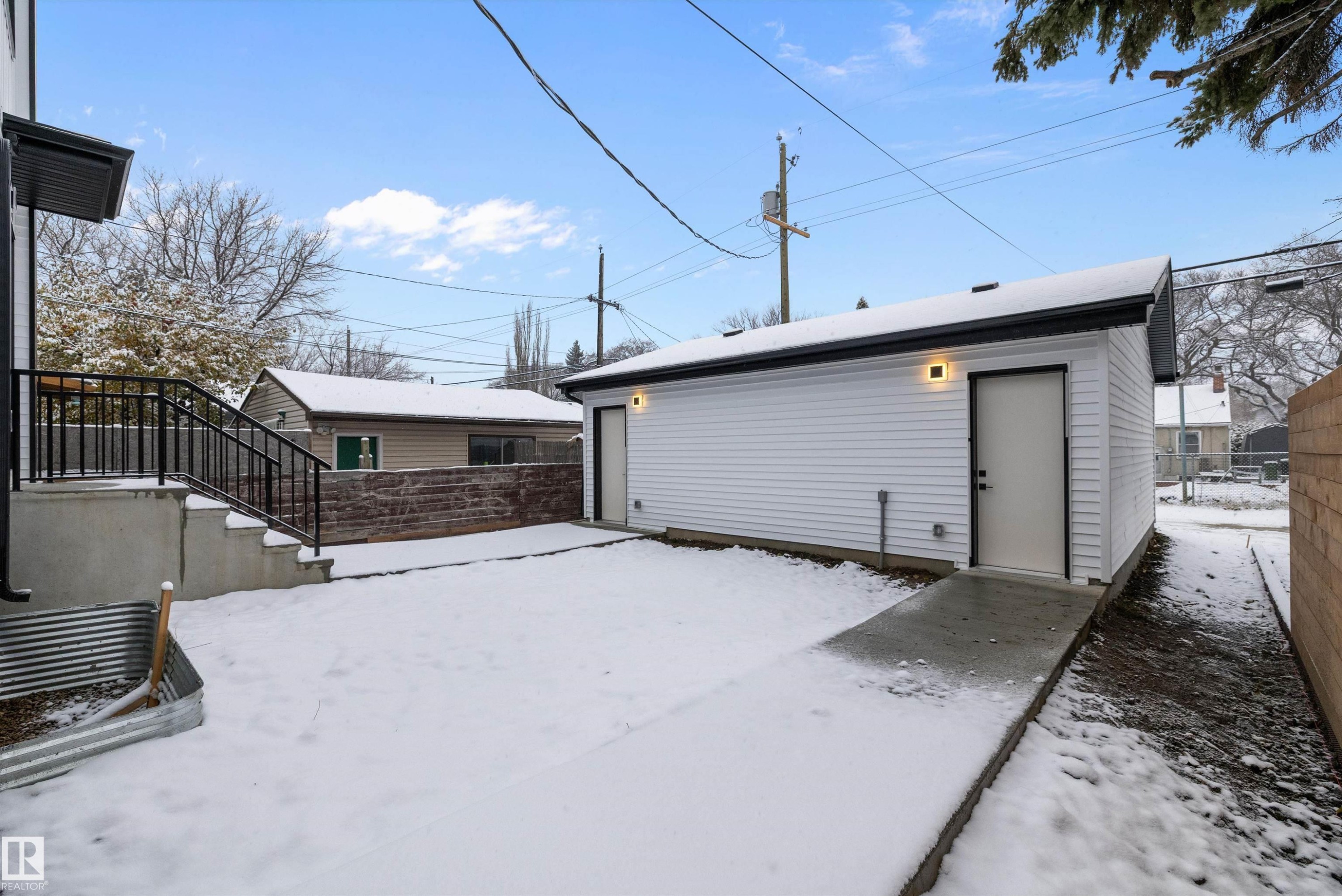 Detached auxiliary building with white siding, a black trim roofline, and two exterior doors - 11418 96 Street, Edmonton, AB - Outdoor With Exterior