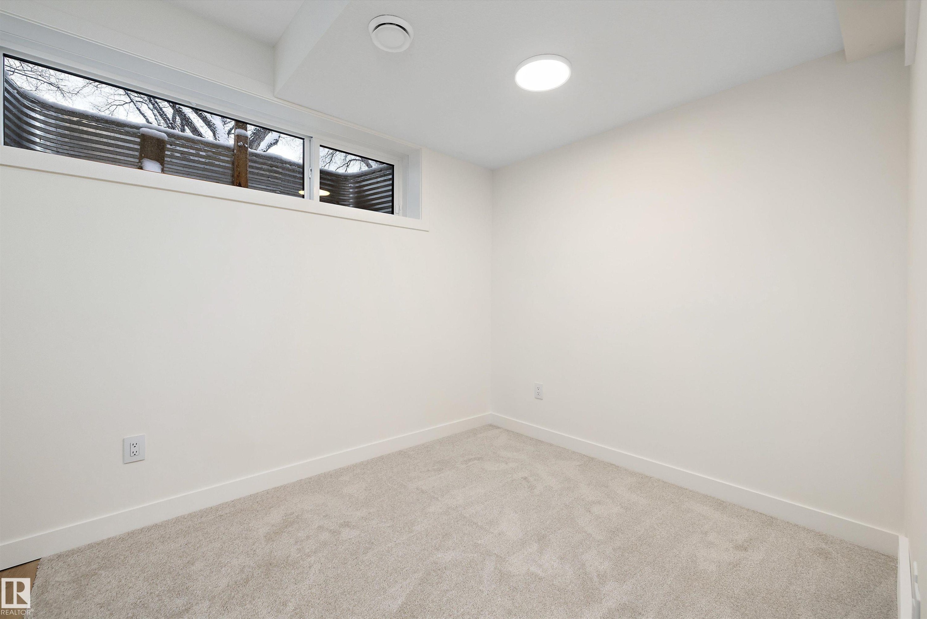 Neutral wall finishes, light-colored carpeting, recessed ceiling lighting, and a horizontal window with window well - 11418 96 Street, Edmonton, AB - Indoor Photo Showing Other Room