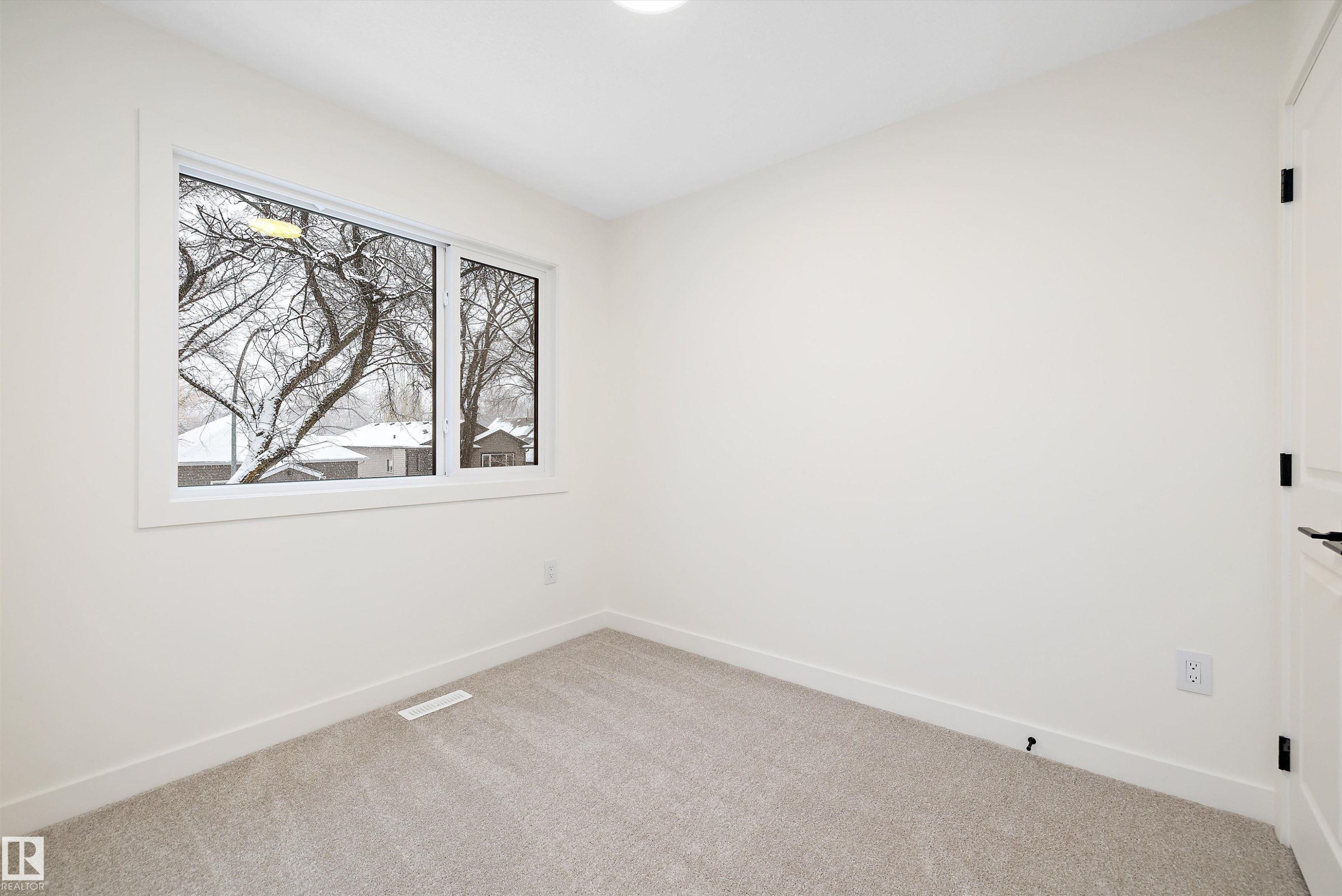 Neutral wall paint with crisp white trim, light gray carpeting, and a window with a white frame - 11418 96 Street, Edmonton, AB - Indoor Photo Showing Other Room