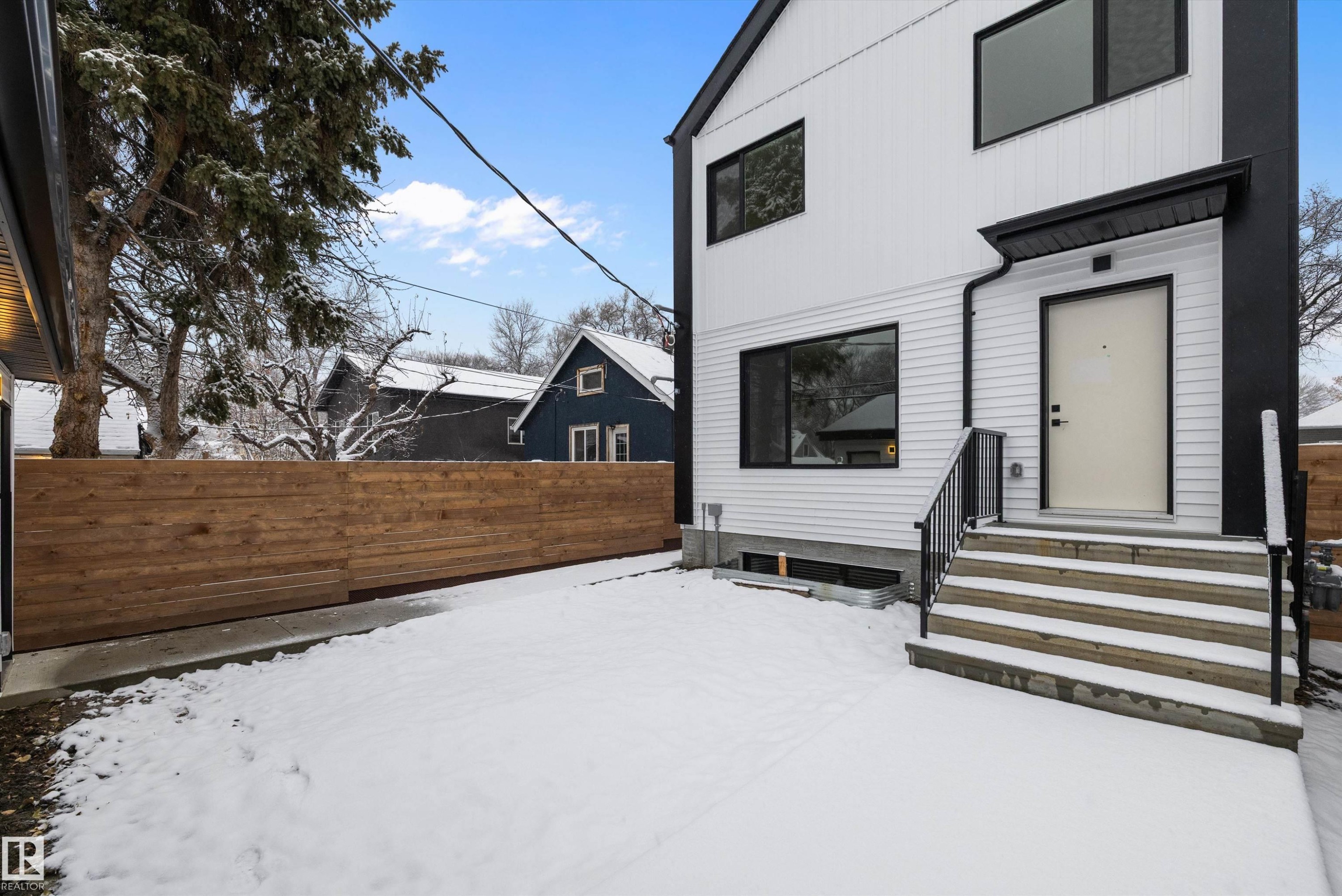 Modern exterior featuring white horizontal siding, black trim, and a prominent entry door - 11418 96 Street, Edmonton, AB - Outdoor