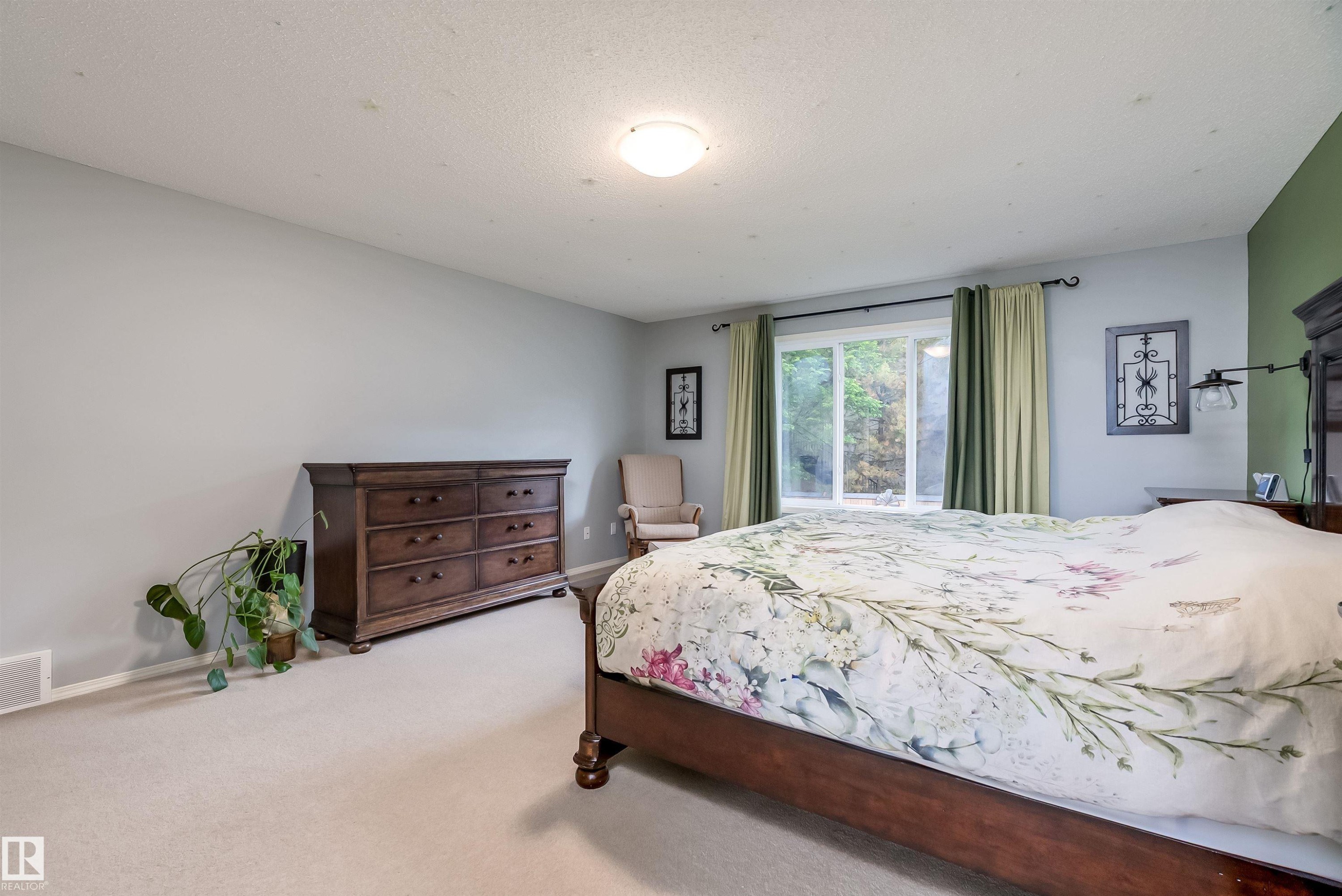 Expansive backyard featuring a wood pergola, a built-in fire pit on a wood-finish deck, a built-in bench with seating, a gravel border, and a raised garden bed with a privacy fence - 59 Rue Monette, Beaumont, AB