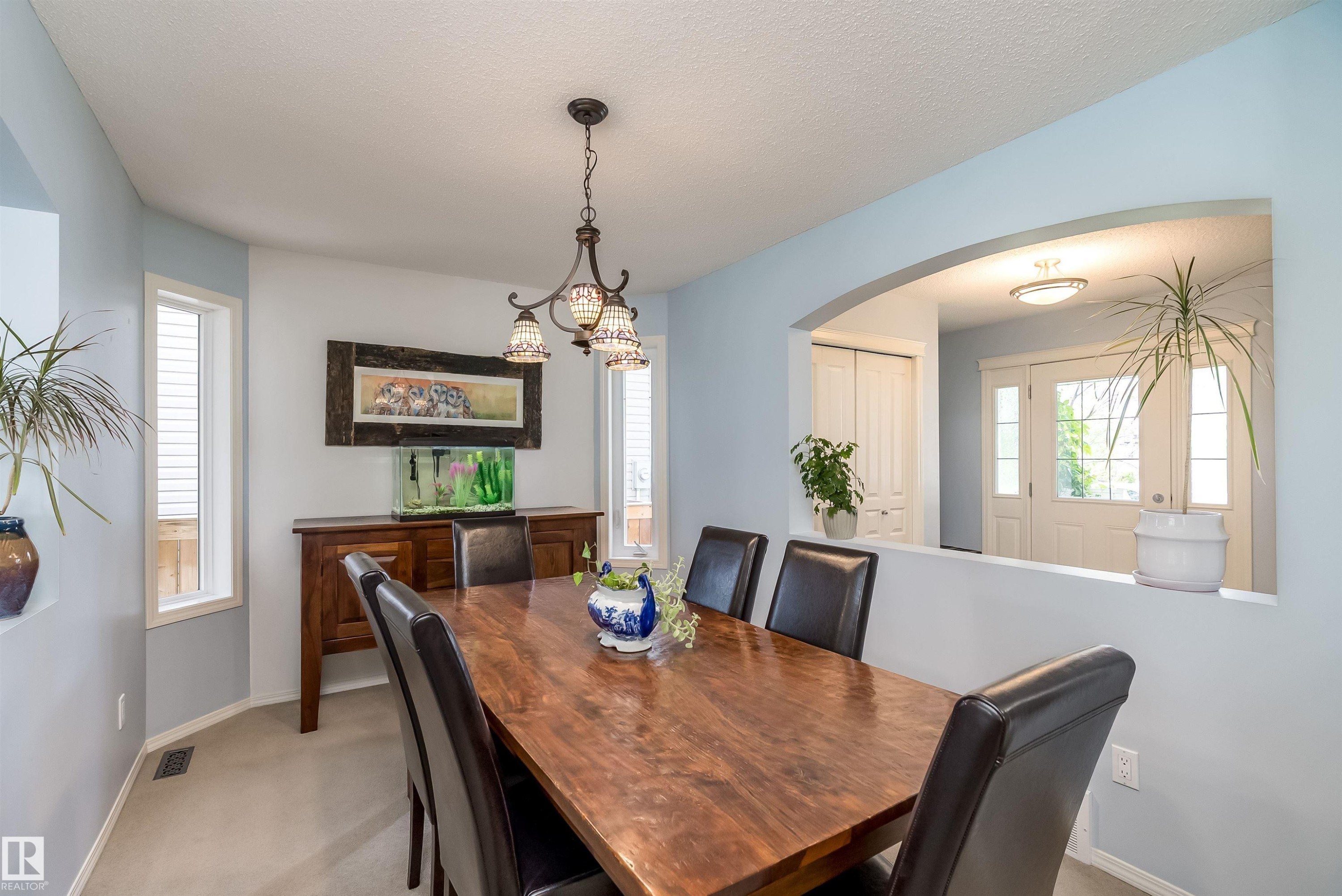 Kitchen featuring white shaker-style cabinetry, stainless steel appliances, dark countertops, and light blue walls - 59 Rue Monette, Beaumont, AB