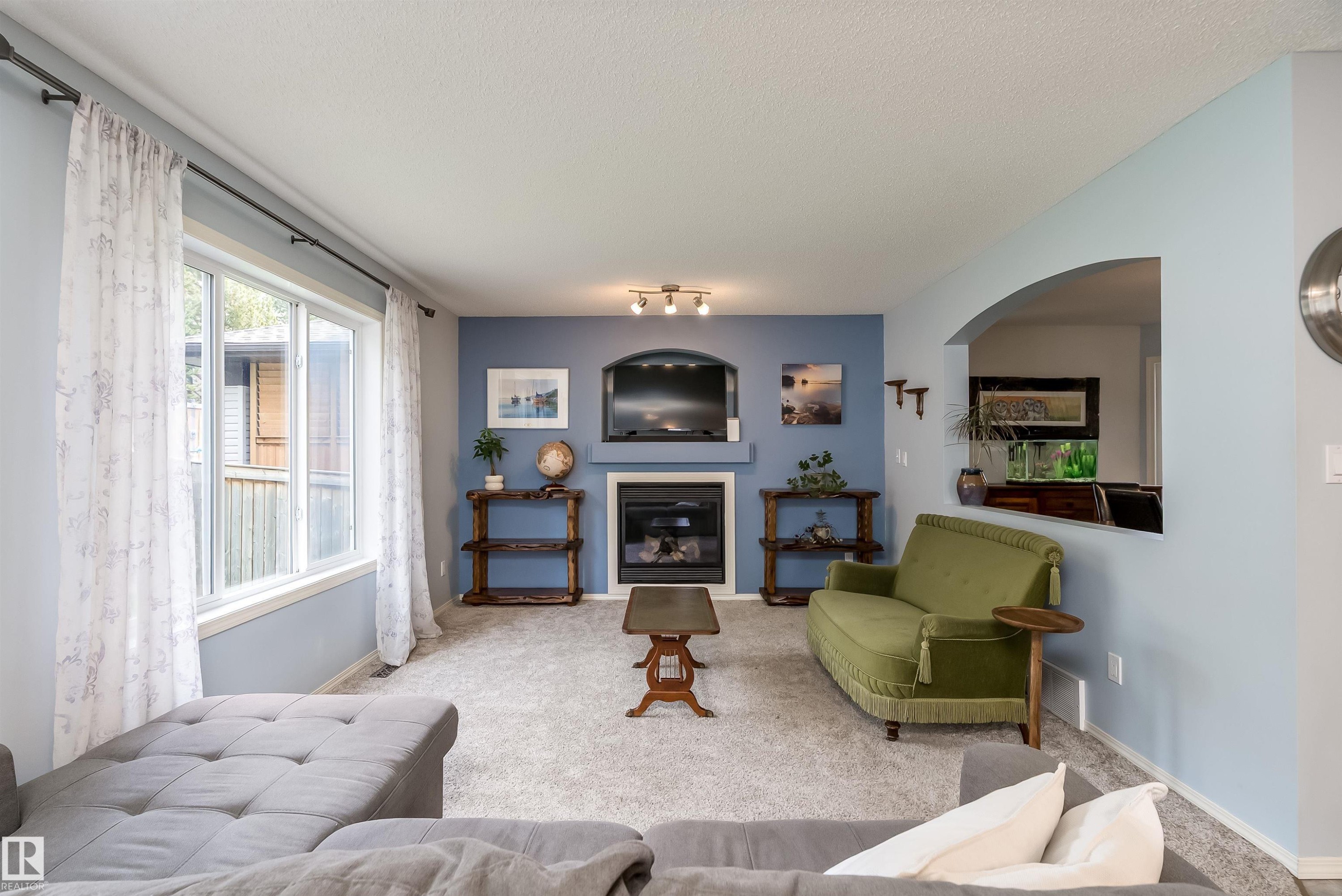 Gourmet kitchen featuring a central island with storage, white cabinetry, integrated stainless steel appliances, patterned backsplash, and tile flooring - 59 Rue Monette, Beaumont, AB