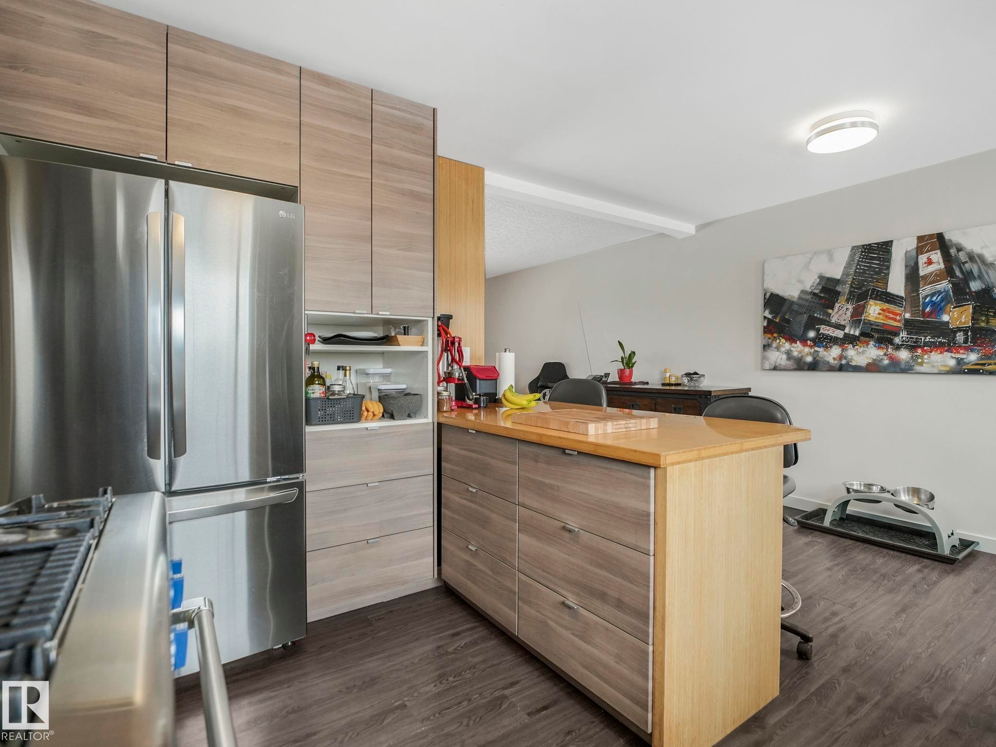 Open-concept kitchen featuring with updated cabinetry, stainless steel refrigerator, and a gas range - 7607 70 Avenue, Edmonton, AB - Indoor Photo Showing Kitchen