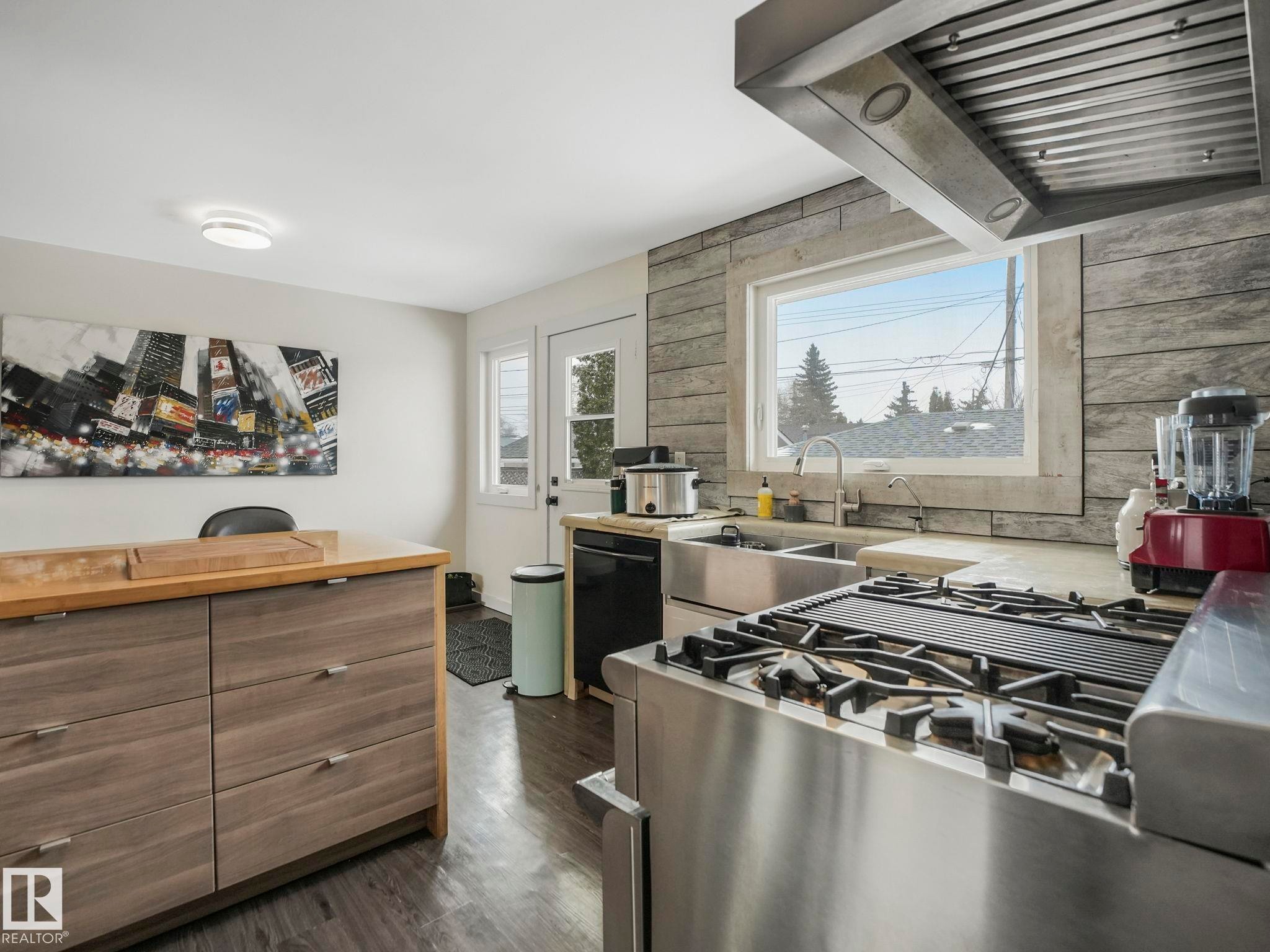 Kitchen featuring a stainless steel range with a griddle, a large window with stone-look surround, a stainless steel double basin sink. - 7607 70 Avenue, Edmonton, AB - Indoor