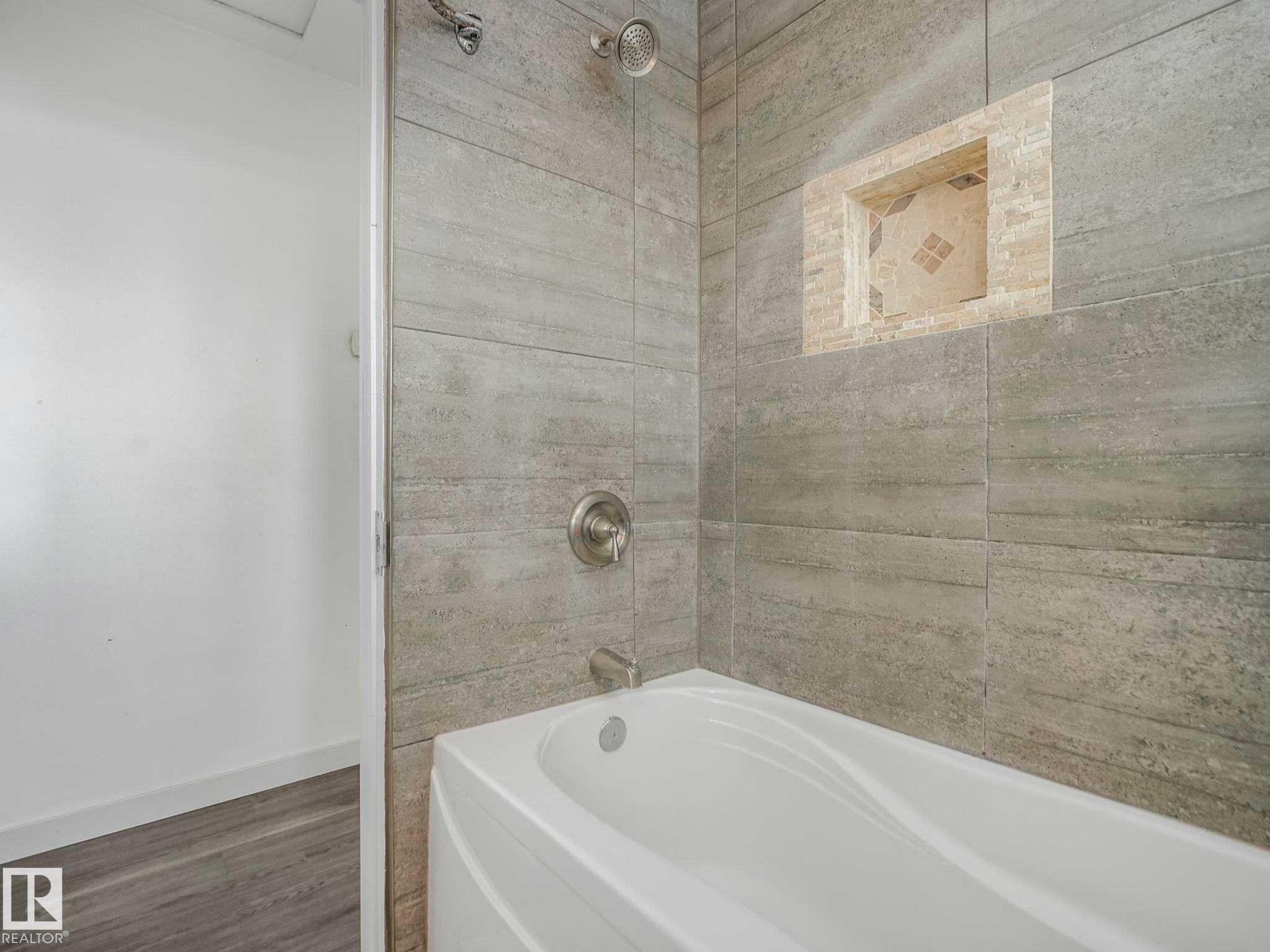 Bathtub with textured gray tile surround - 7607 70 Avenue, Edmonton, AB - Indoor Photo Showing Bathroom