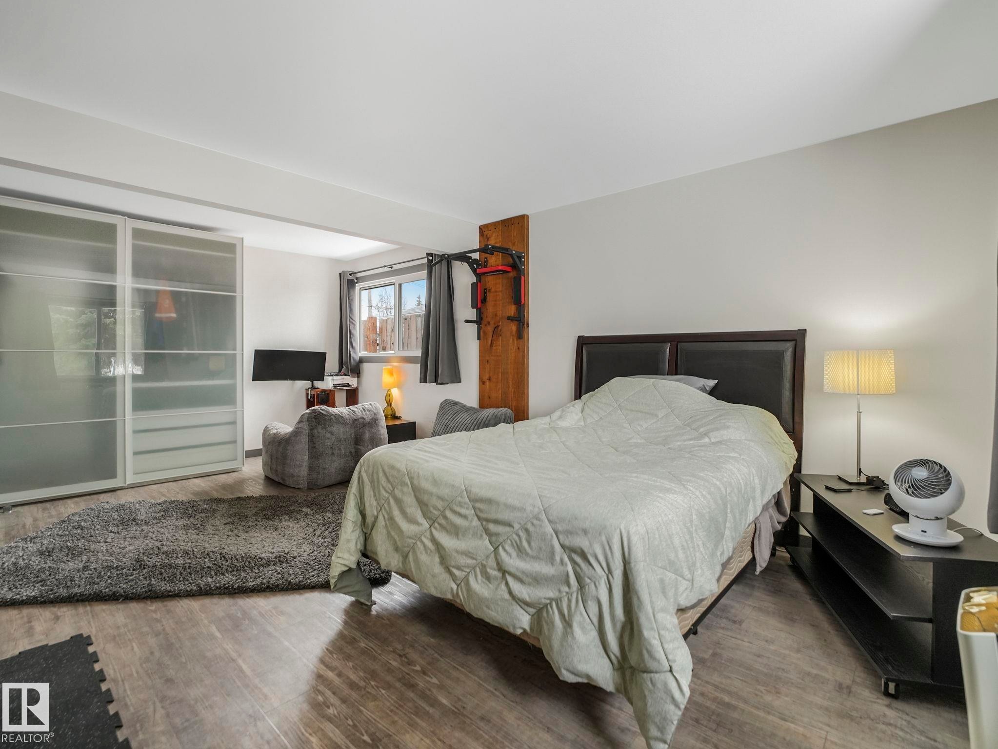 Oversized room with a built-in closet with frosted sliding doors, and ample natural light from the window - 7607 70 Avenue, Edmonton, AB - Indoor Photo Showing Bedroom