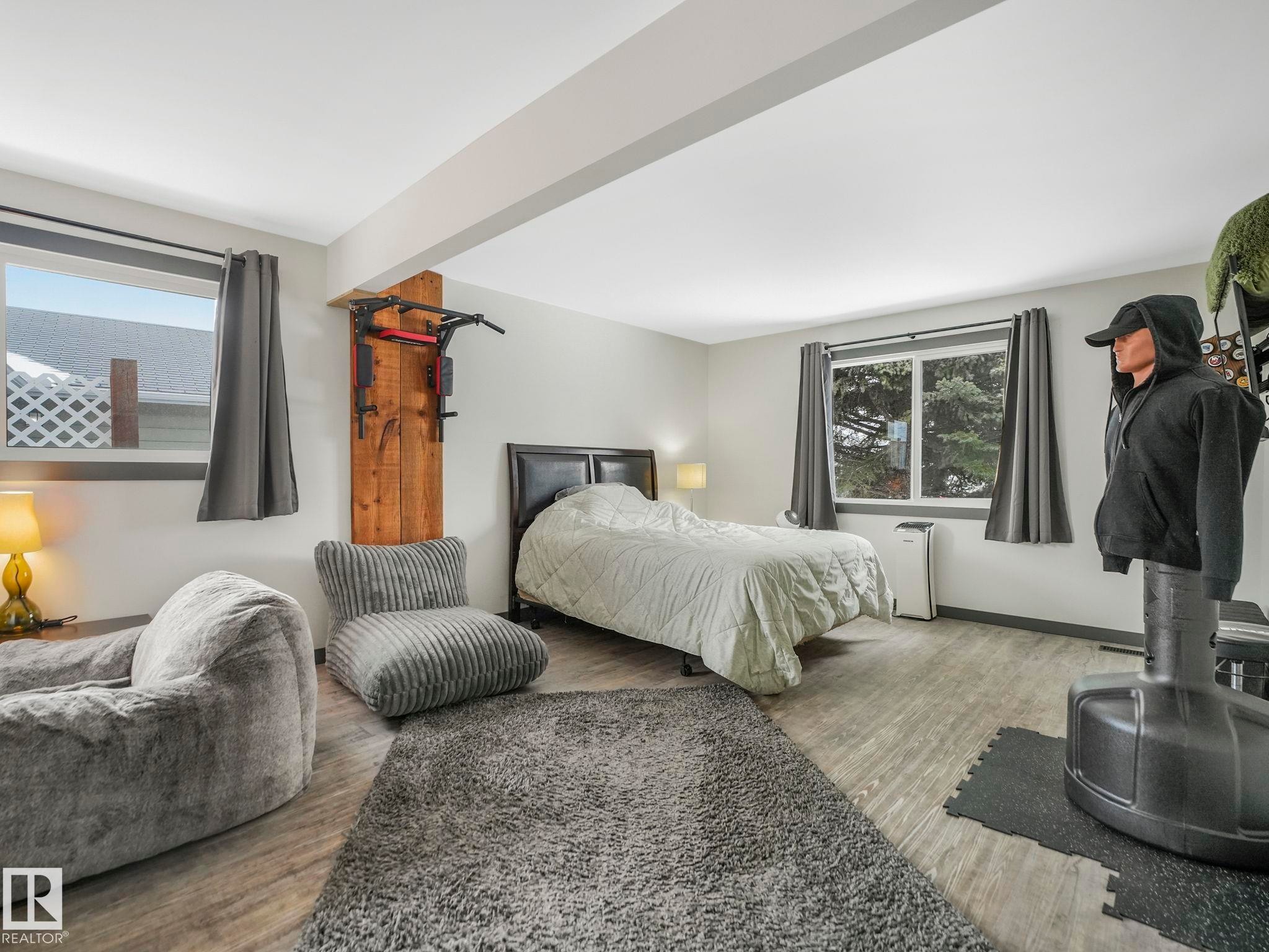 Spacious room with two large windows and dark drapery, recessed lighting, and a built-in wooden accent wall - 7607 70 Avenue, Edmonton, AB - Indoor Photo Showing Bedroom