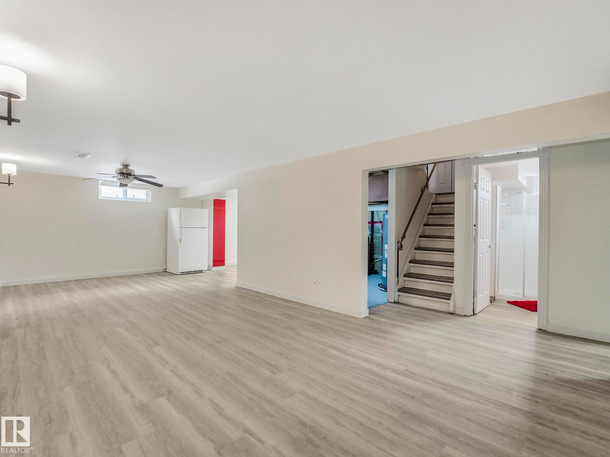 Spacious basement living room with recessed lighting, a ceiling fan, and a built-in staircase - 7607 70 Avenue, Edmonton, AB - Indoor Photo Showing Other Room