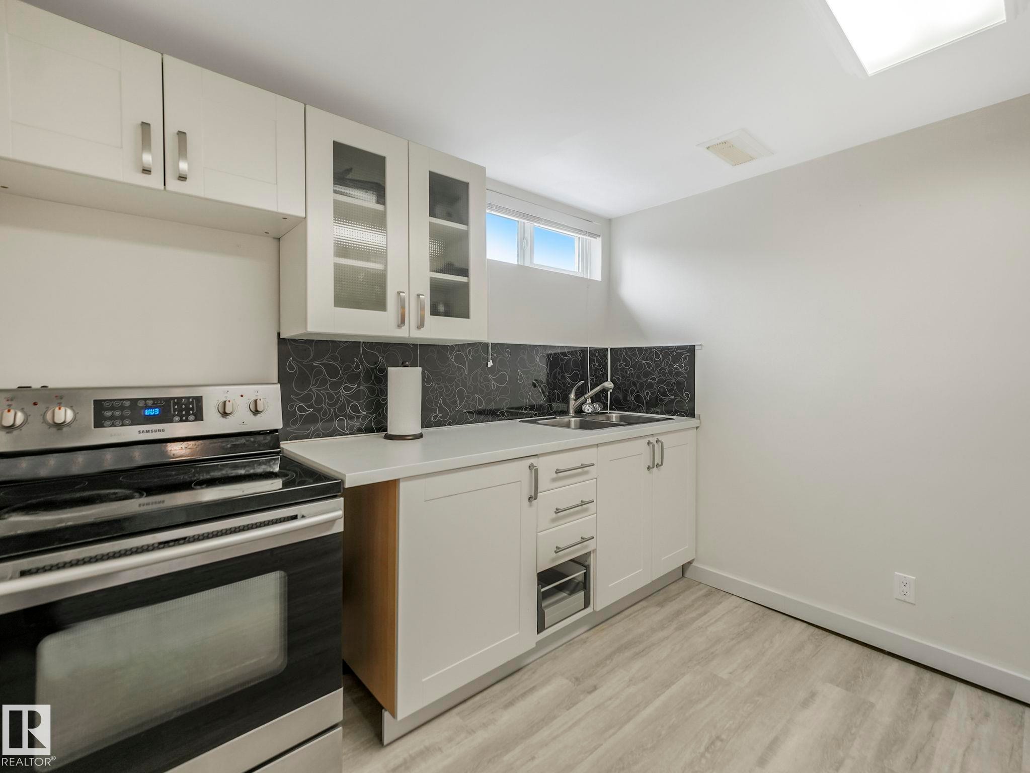 Basement Kitchenette featuring white cabinetry, a stainless steel range, a single basin sink, white countertops. - 7607 70 Avenue, Edmonton, AB - Indoor Photo Showing Kitchen With Double Sink